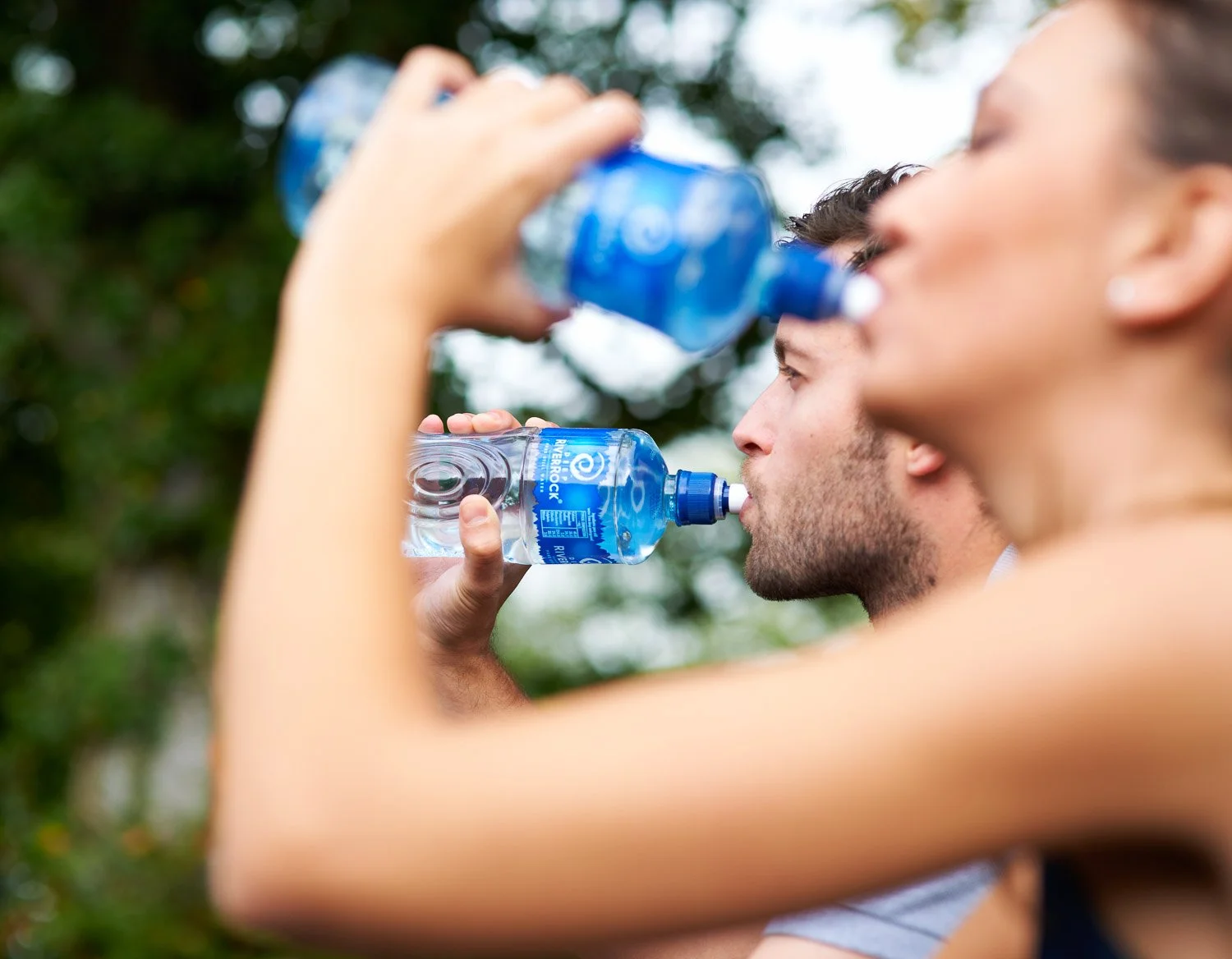 A couple drinking Deep RiverRock bottled water outdoors after exercise during a lifestyle commercial photography shoot for Coca-Cola.