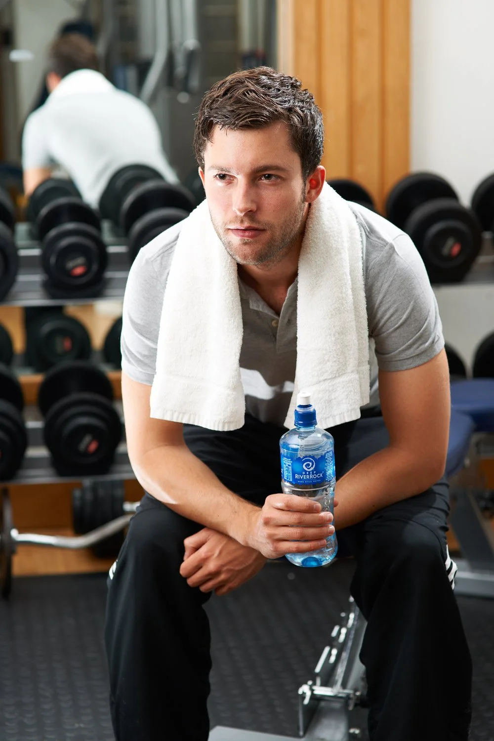 Man drinking Deep RiverRock water during a workout in a gym as part of a commercial lifestyle photography campaign.