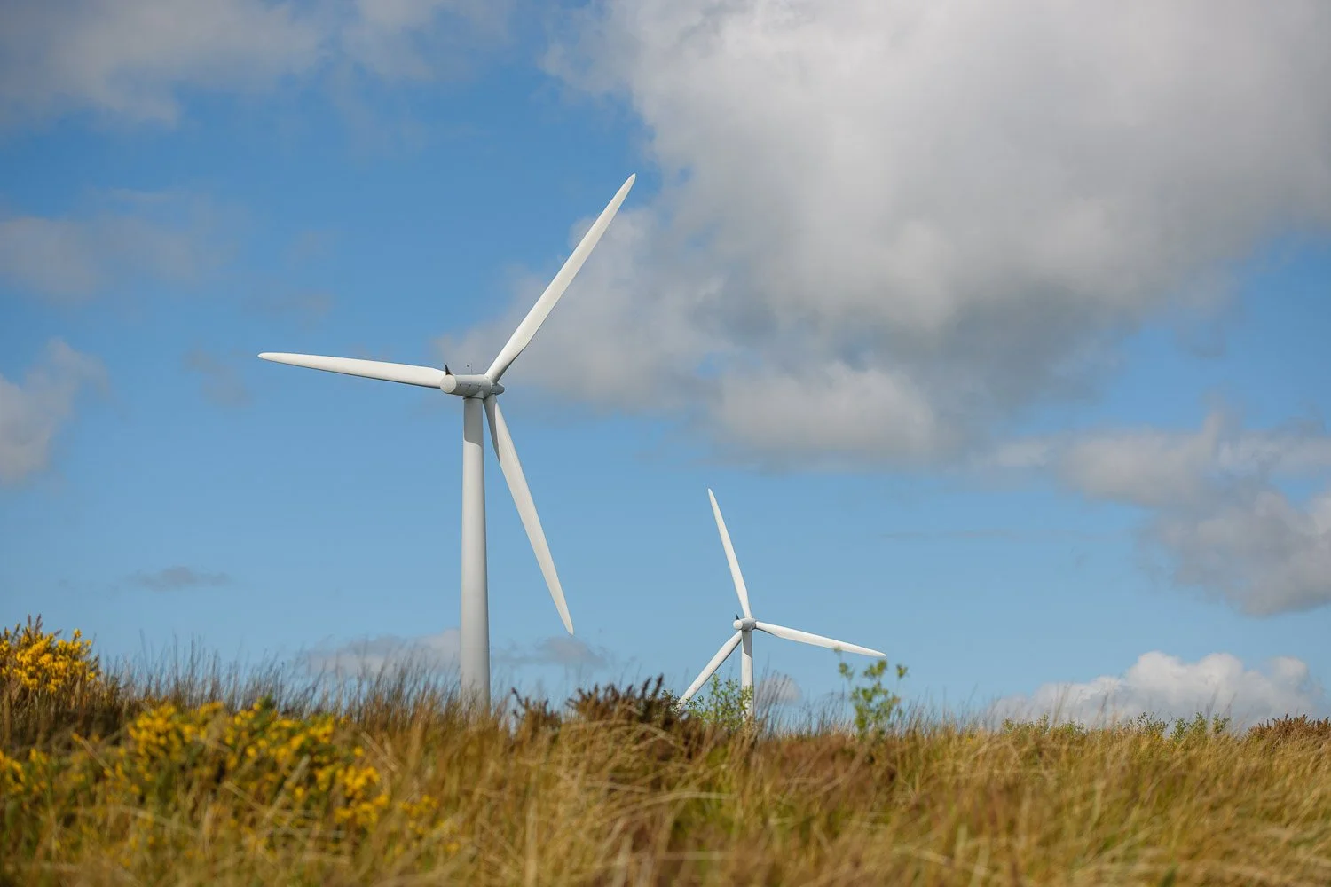 Close-up of wind turbine blades against a blue sky, industrial photography by David Cordner