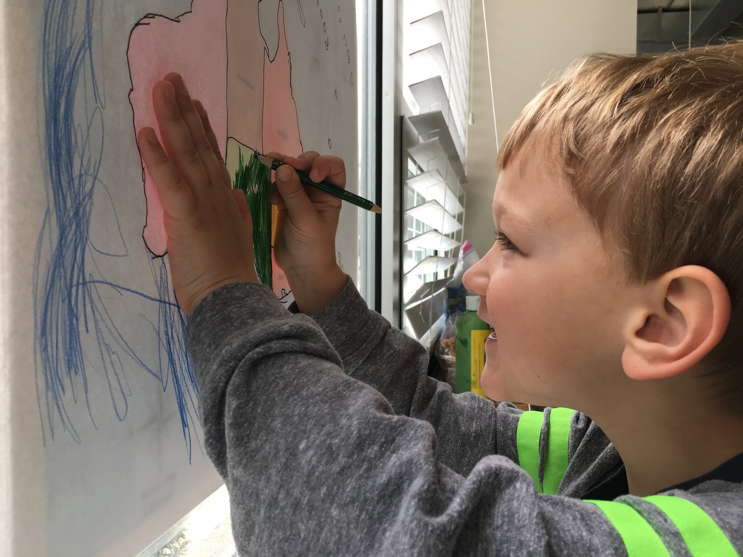 A child traces and colors the map of Oceania on the windowpane.