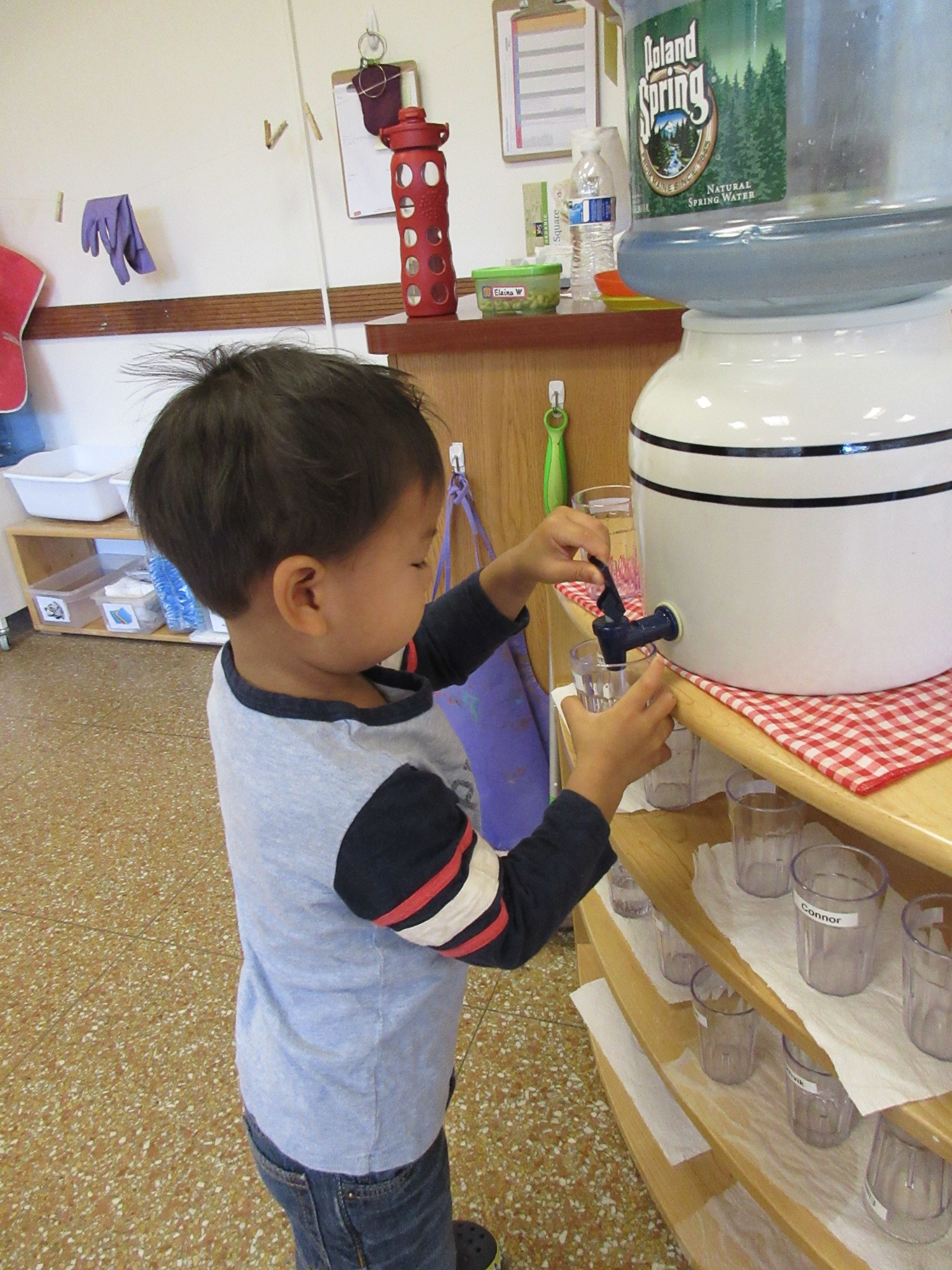 A useful Practical Life exercise is learning to pour water from the dispenser into a cup with control and ease.