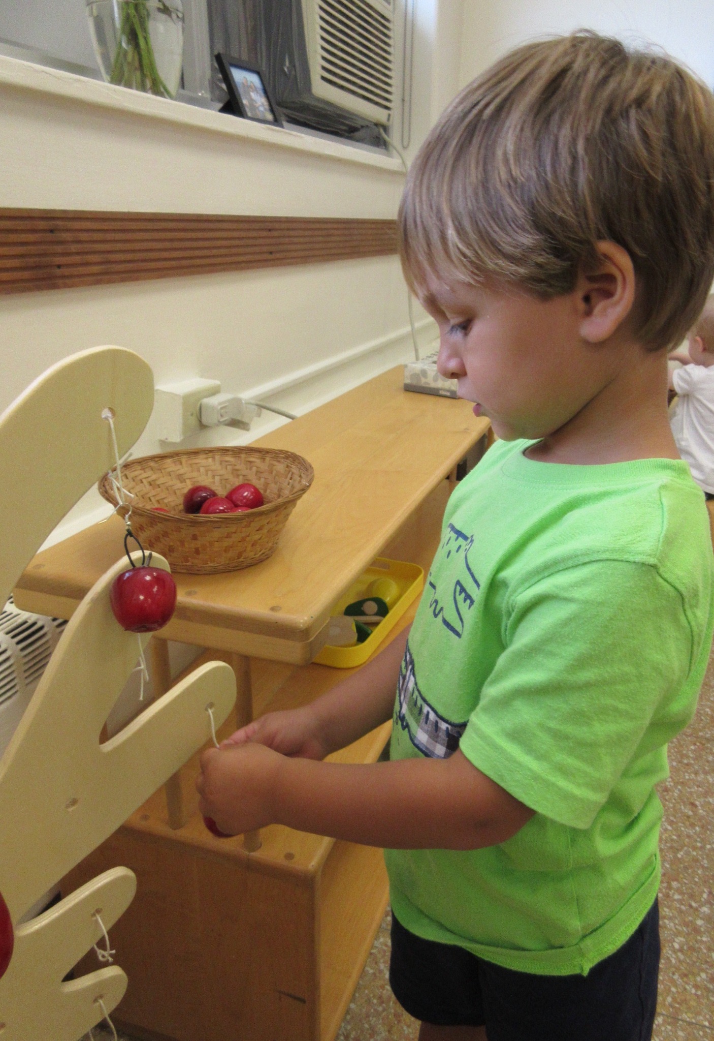 Using hand-eye coordination to carefully hook the apples on our wooden tree