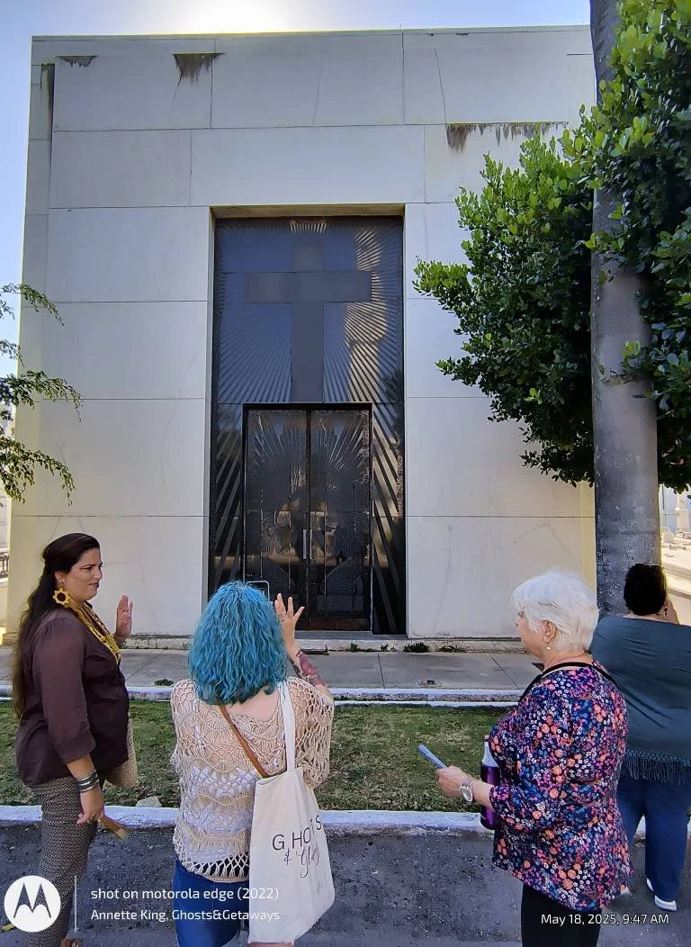 People standing outside a building with a prominent cross and religious imagery on the glass door, engaged in a conversation.