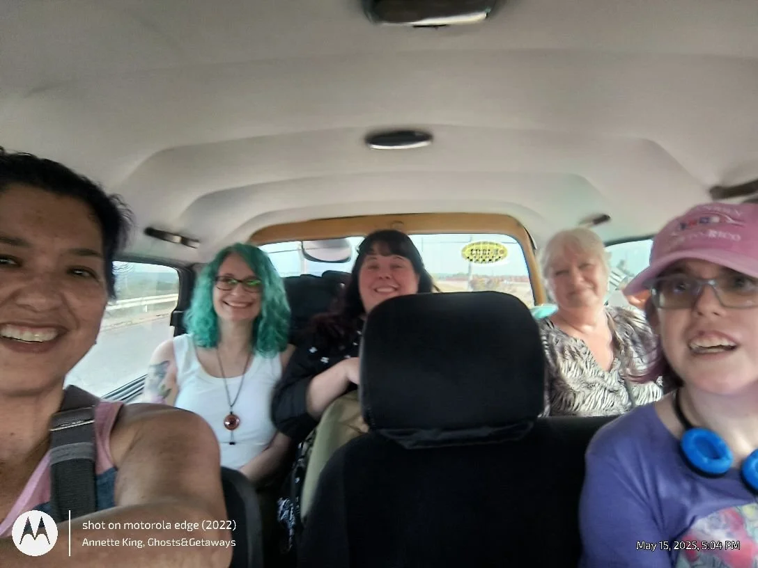 Group of five women smiling inside a vehicle during daytime.