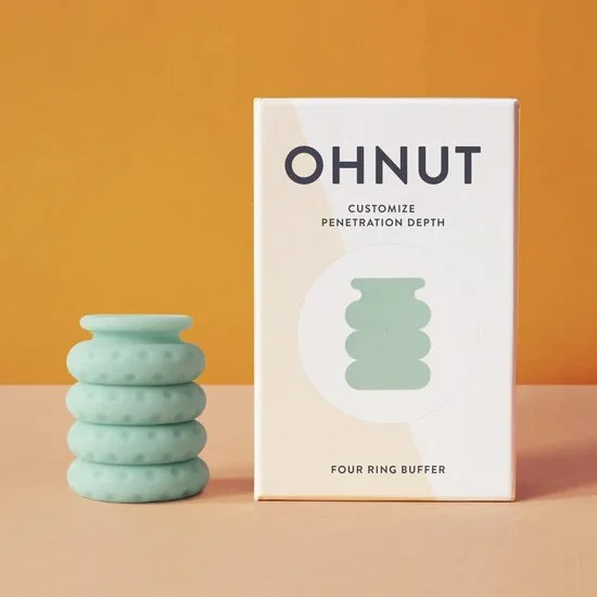 A white box with black text that reads 'OHNUT Customize Penetration Depth Four Ring Buffer' next to a stack of four mint green silicone rings.