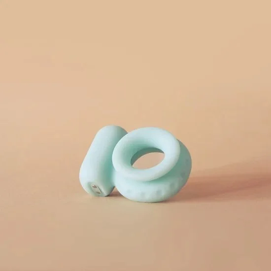 Light green wireless earbuds resting on a beige surface with a beige background.