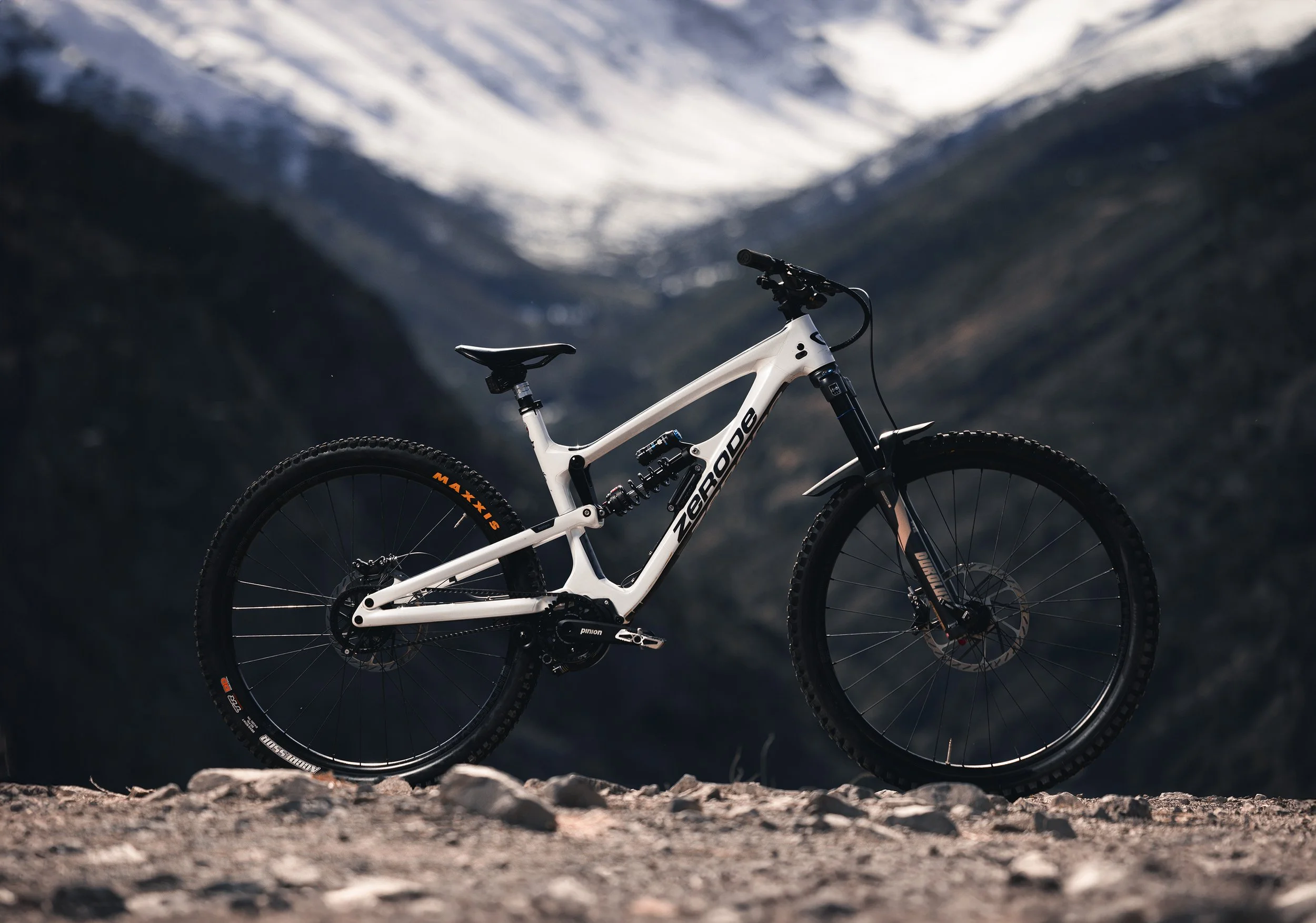 White electric mountain bike on rocky terrain in front of a mountain landscape
