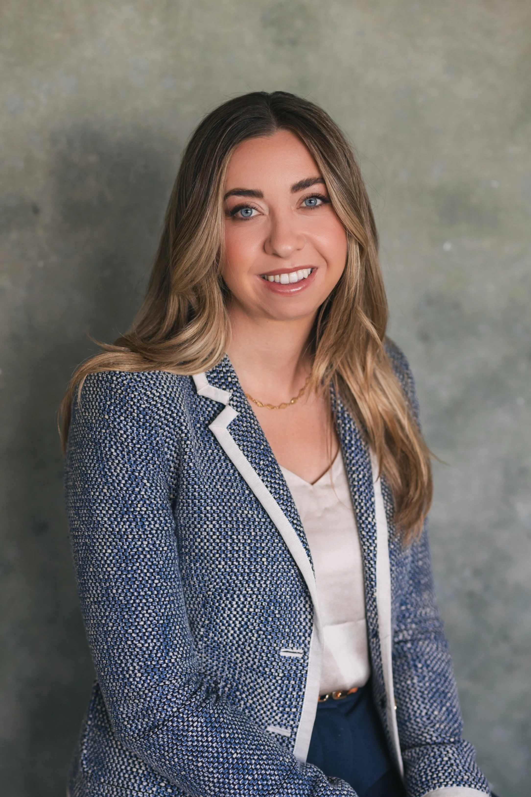 A professional portrait of Ellen Sutherland, founder and lead counsel at Sutherland Criminal Defence, smiling while wearing a blue blazer and white blouse against a neutral studio background.