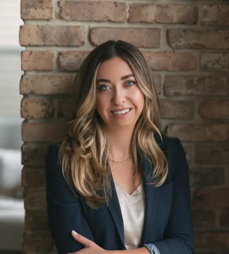 A professional portrait of Ellen Sutherland, founder and lead counsel of Sutherland Criminal Defence, smiling while wearing a navy blazer and white top in front of a brick wall.