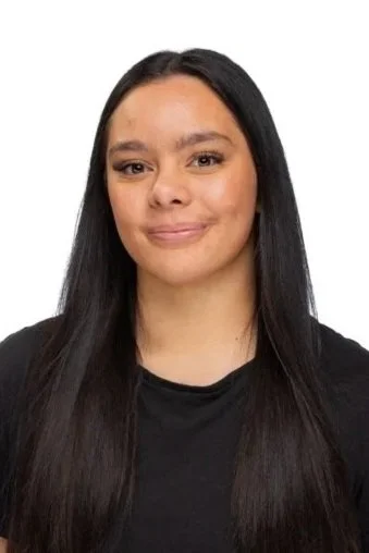 A woman who is a dance teacher at Arc Dance school in Grey Lynn, Auckland, with long black hair, wearing a black shirt, smiling lightly at the camera.