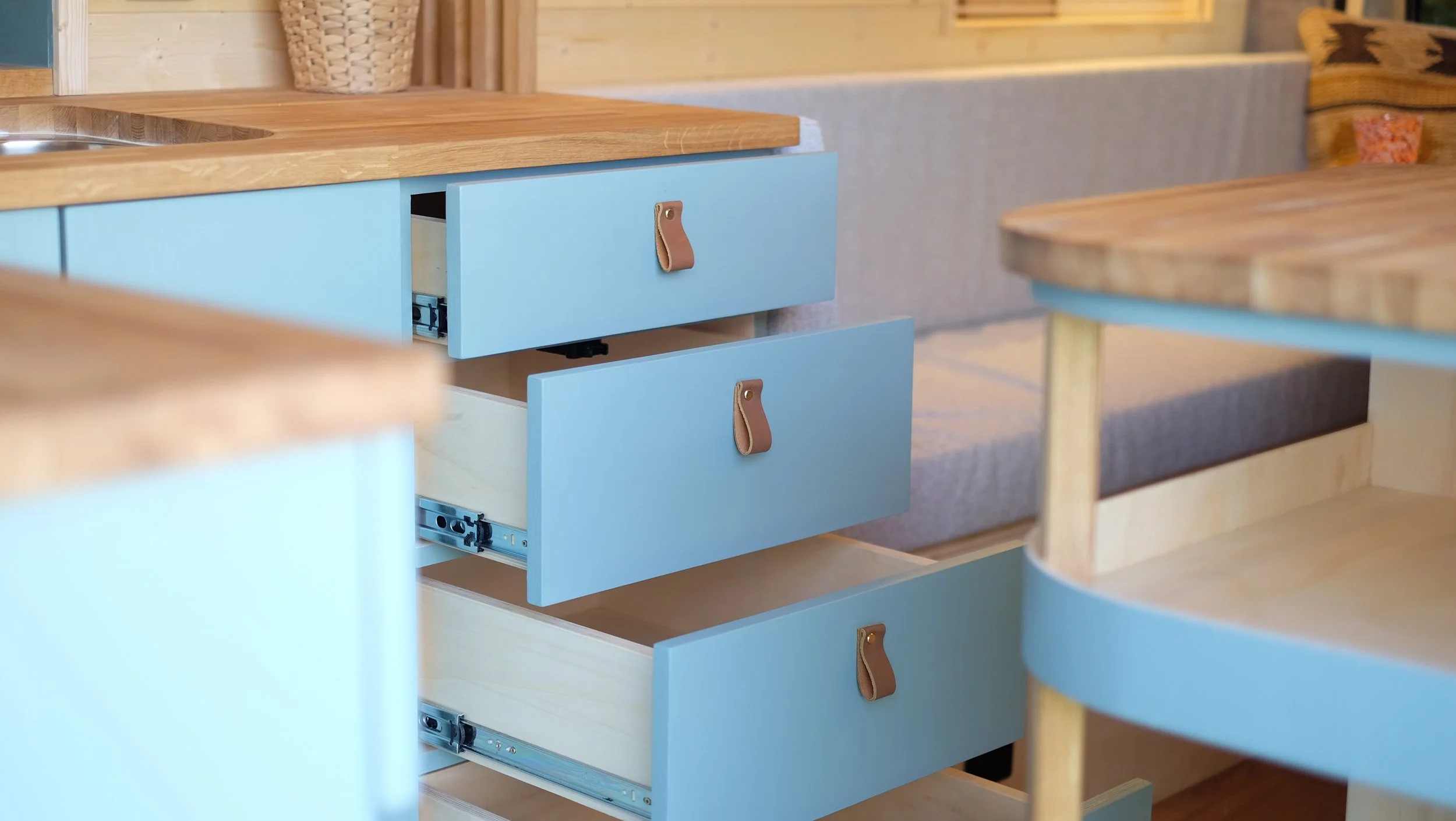 Open light blue drawers with leather pull tabs, revealing empty interior, in a cozy wooden and upholstered room.