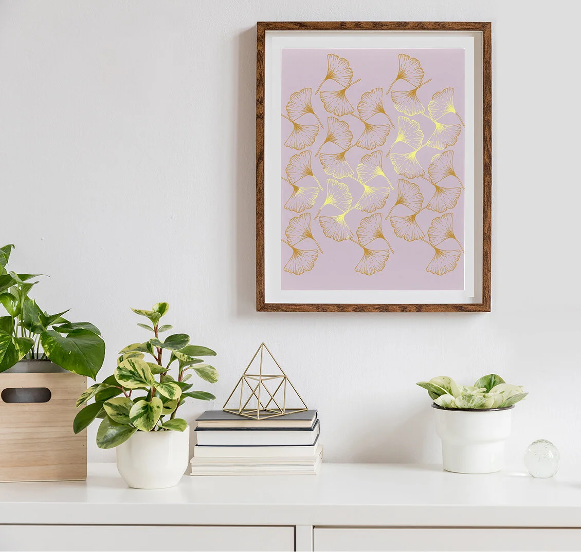 Framed print of ginkgo leaves, displayed in a minimalist setting with neutral tones.