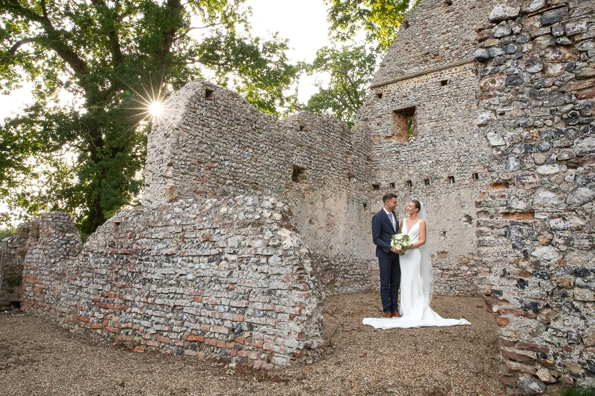 Mr & Mrs Jermy wide landscape shot taken on grounds of Bateman Barns in old church ruins with the sun beaming through at sunset