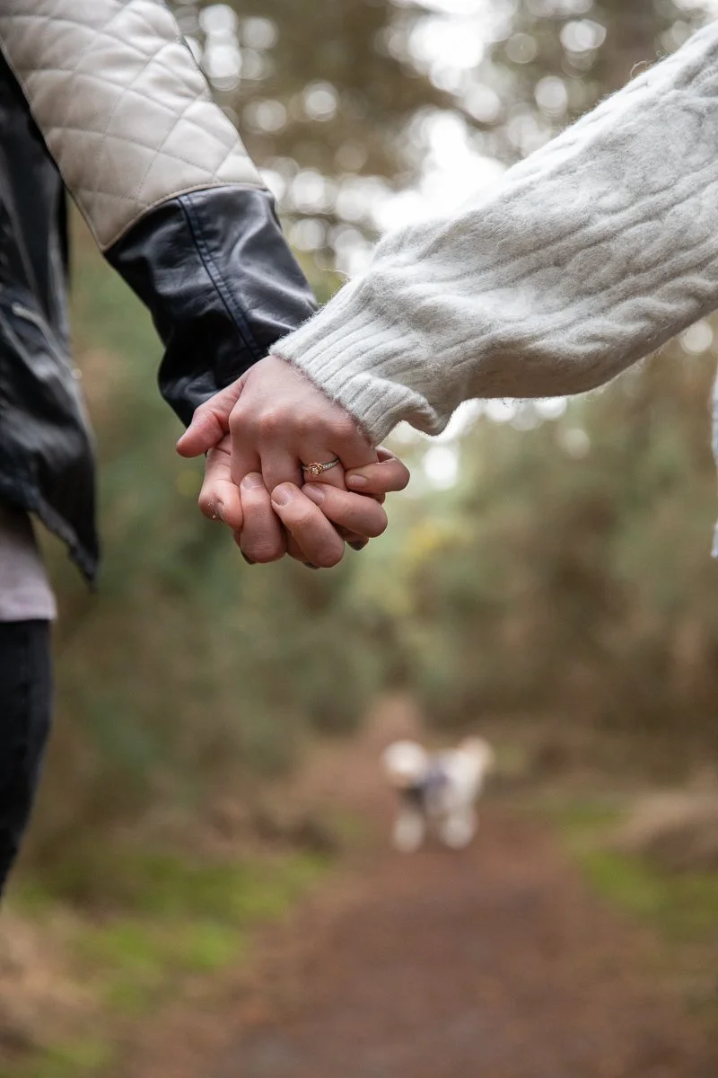 Engagement photo taken in Norfolk woods of two hands holding together and an engagement ring on the women's finger