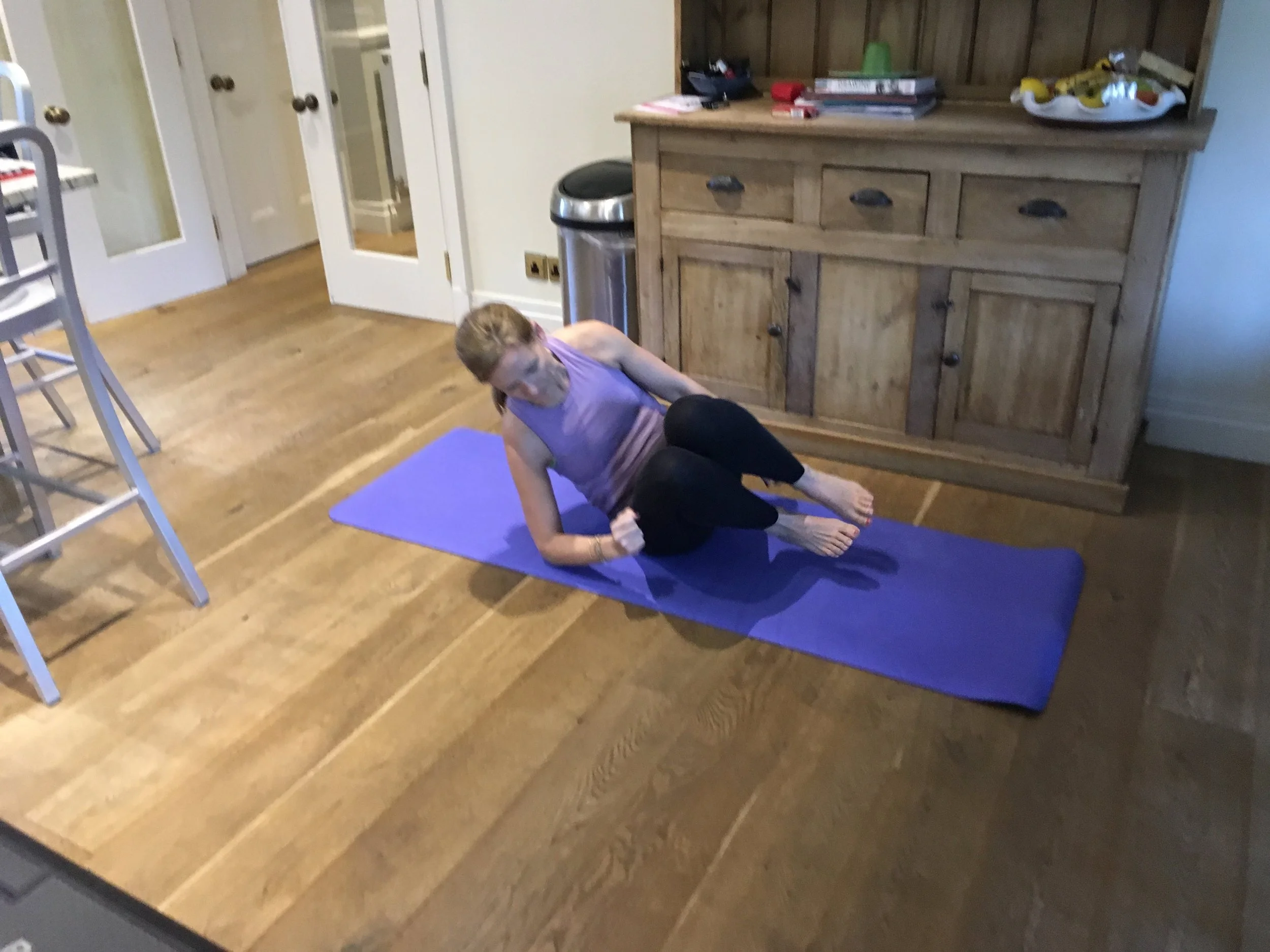 Core workout with a personal training client at her home in the kitchen