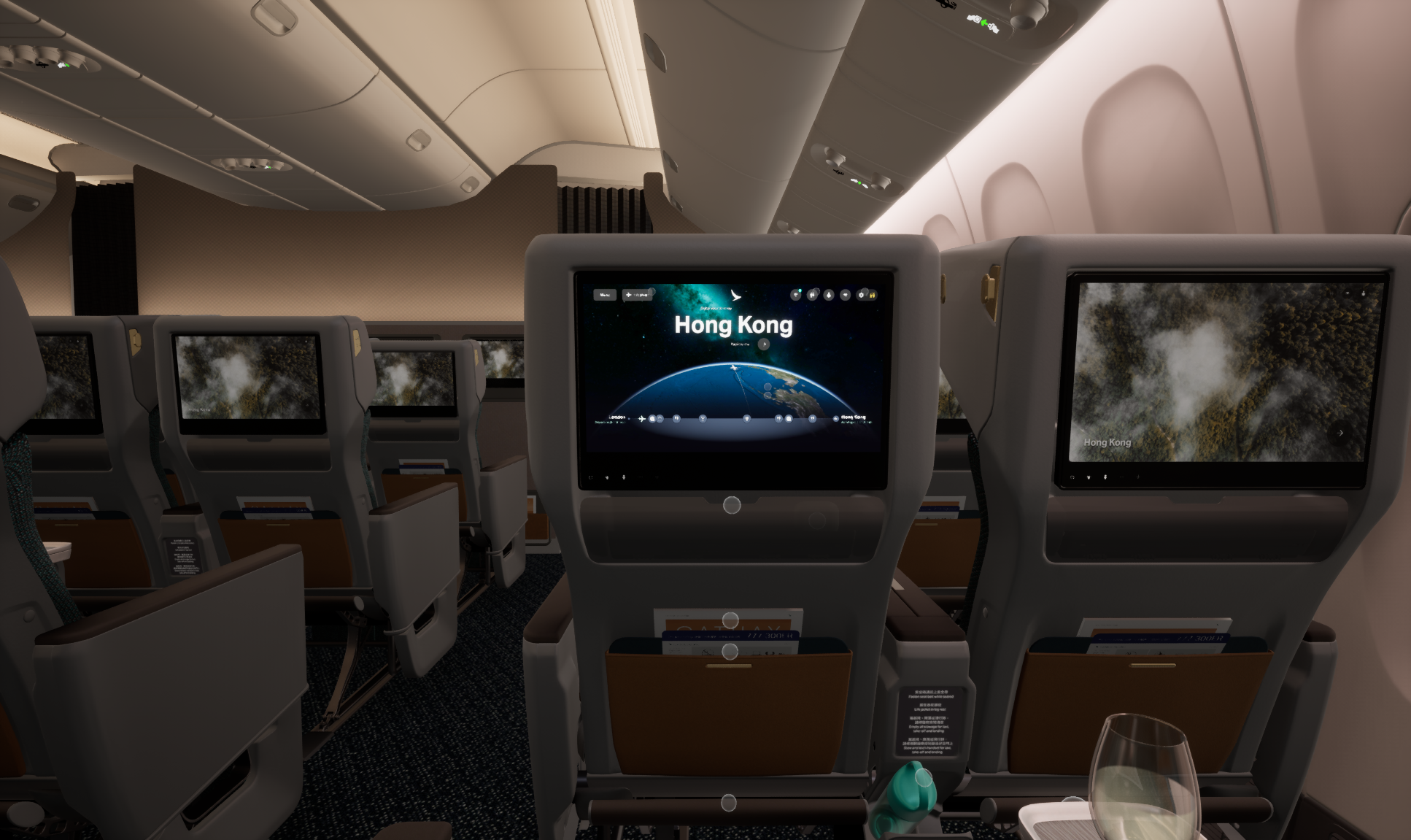 View of an airplane cabin interior showing multiple seats with built-in entertainment screens. The middle screen displays a map with the labels 'Hong Kong' and 'London.'