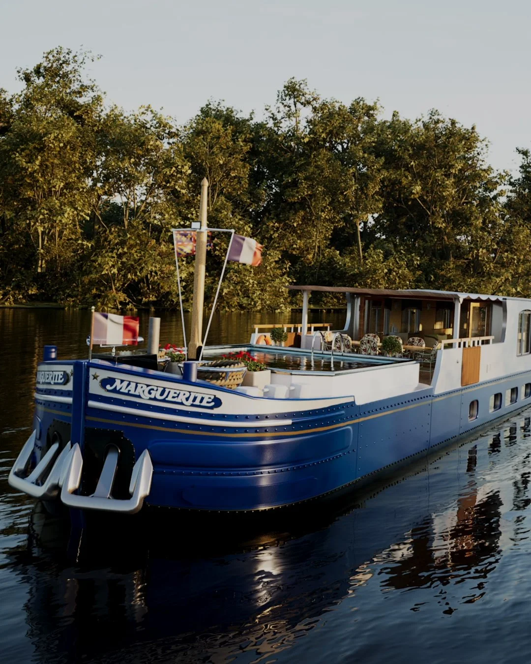 A blue houseboat named 'Marguerite' on a calm river, with trees in the background, decorated with flags and outdoor furniture on the deck.