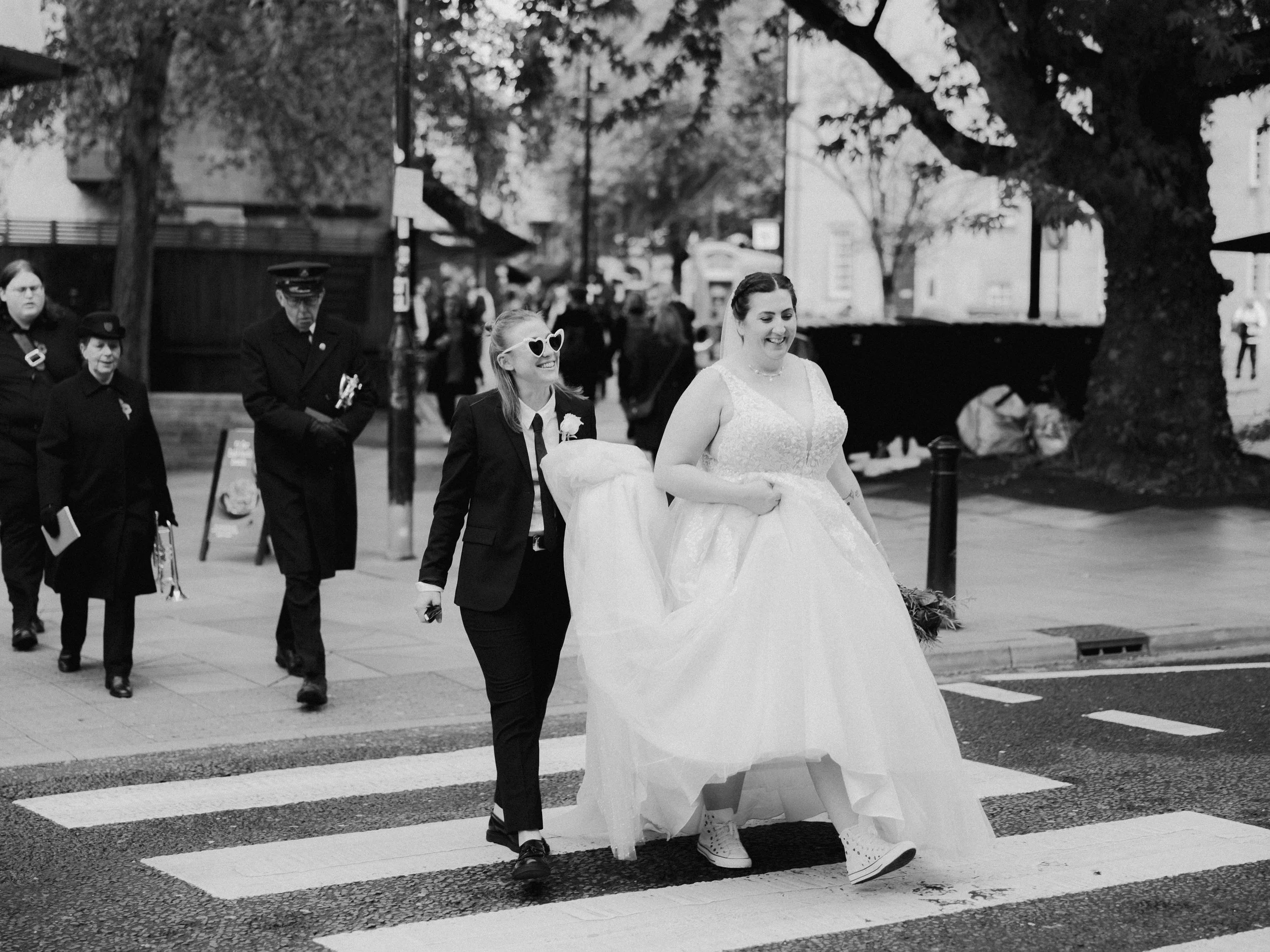A black and white image of two newly married brides crossing a road in Bath.