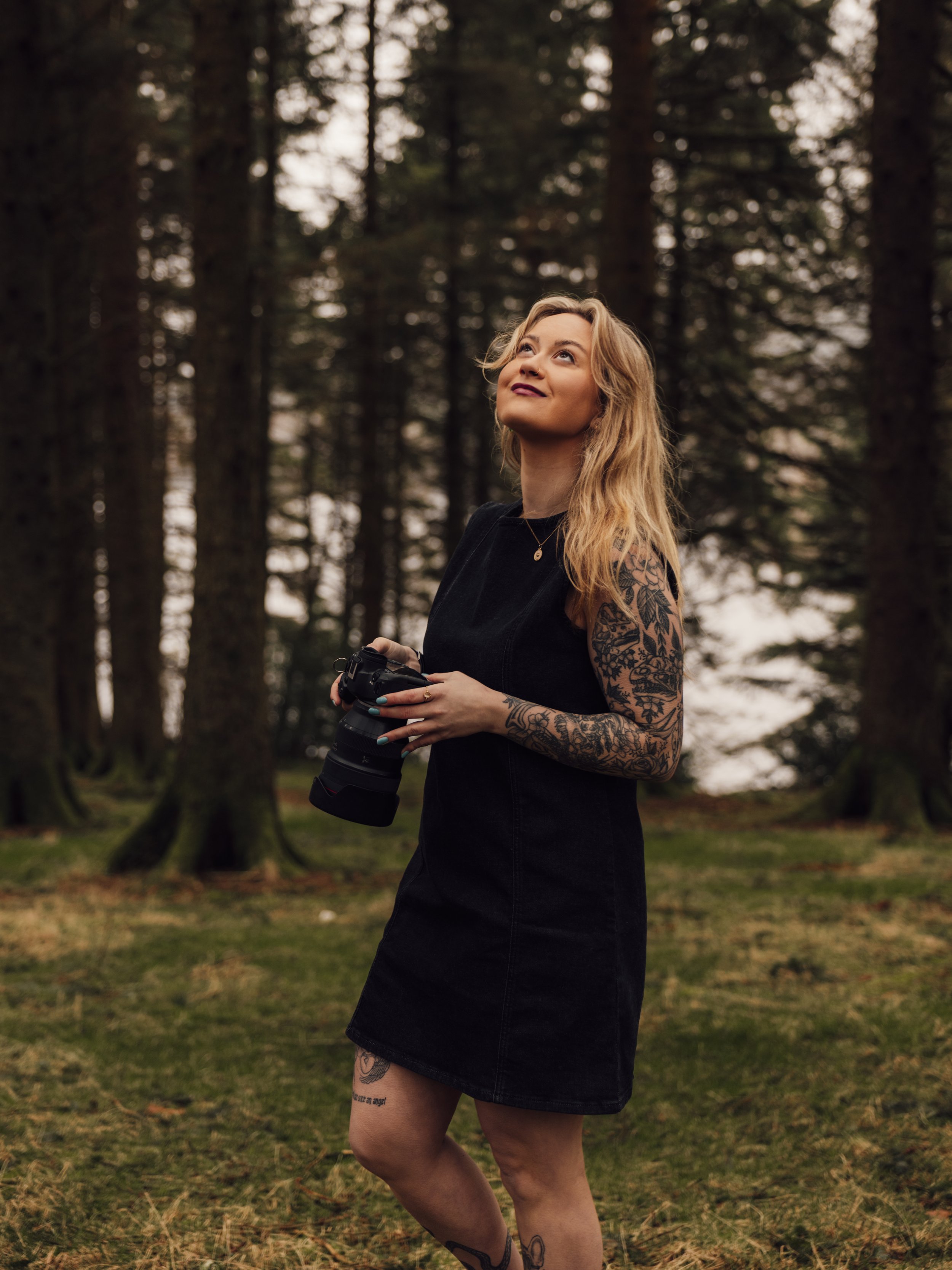 Documentary wedding photographer based in South Wales, laughing naturally while standing in the woods with a camera