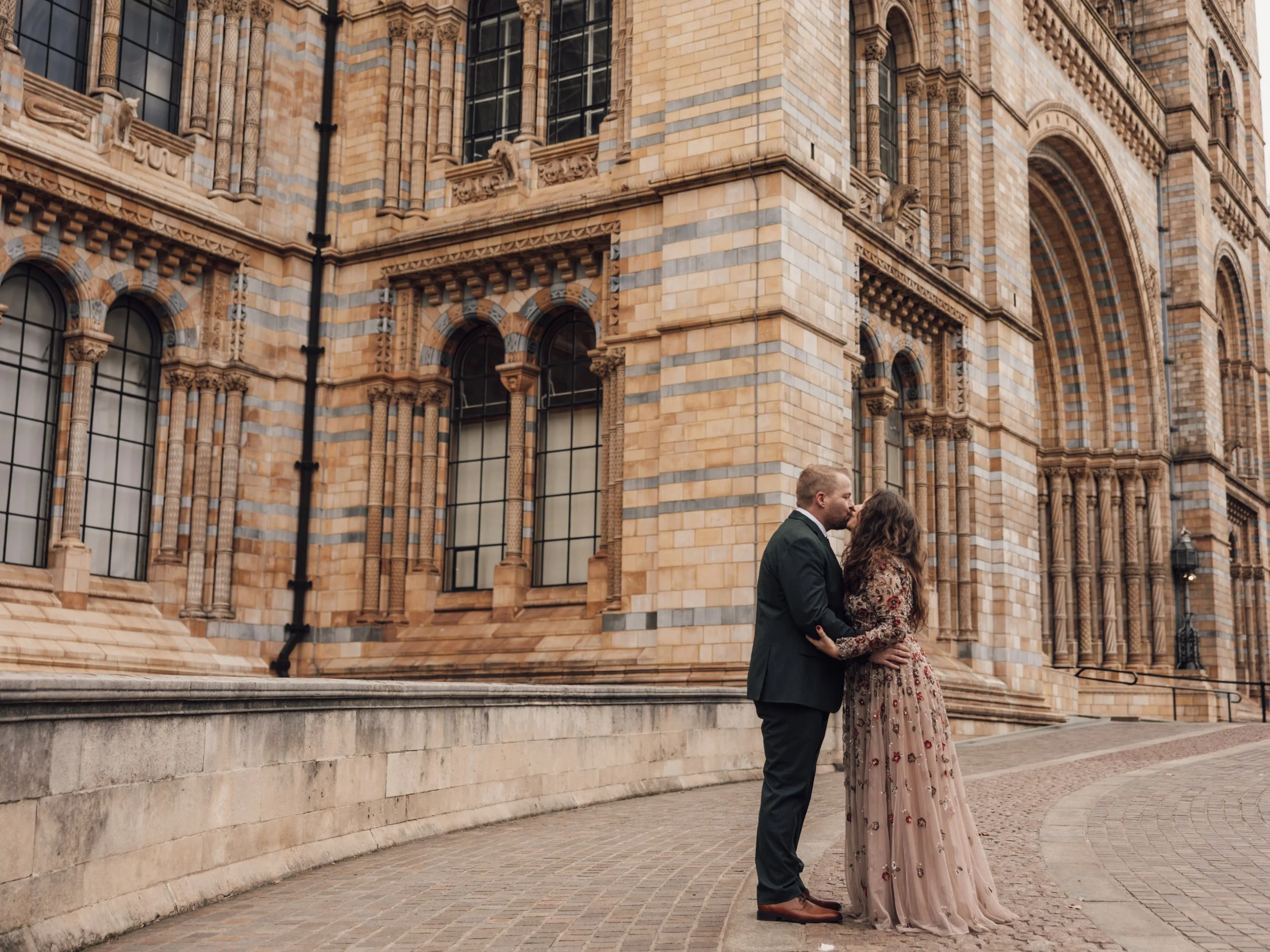 Couple sharing a kiss outside the Natural History Museum in London during their romantic elopement.