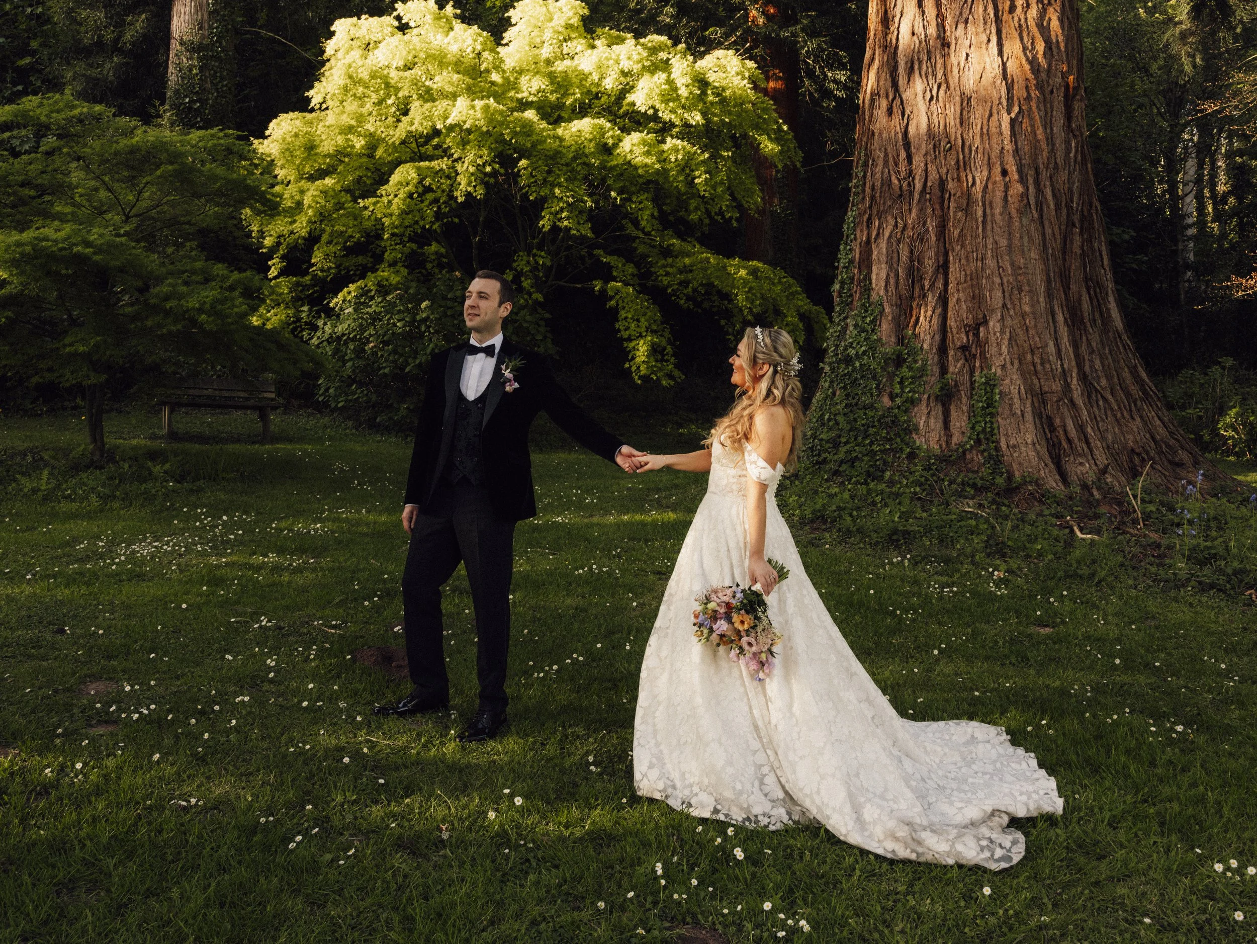Newly married couple standing under a huge red wood tree at New house country hotel while the evening light shines down on them.