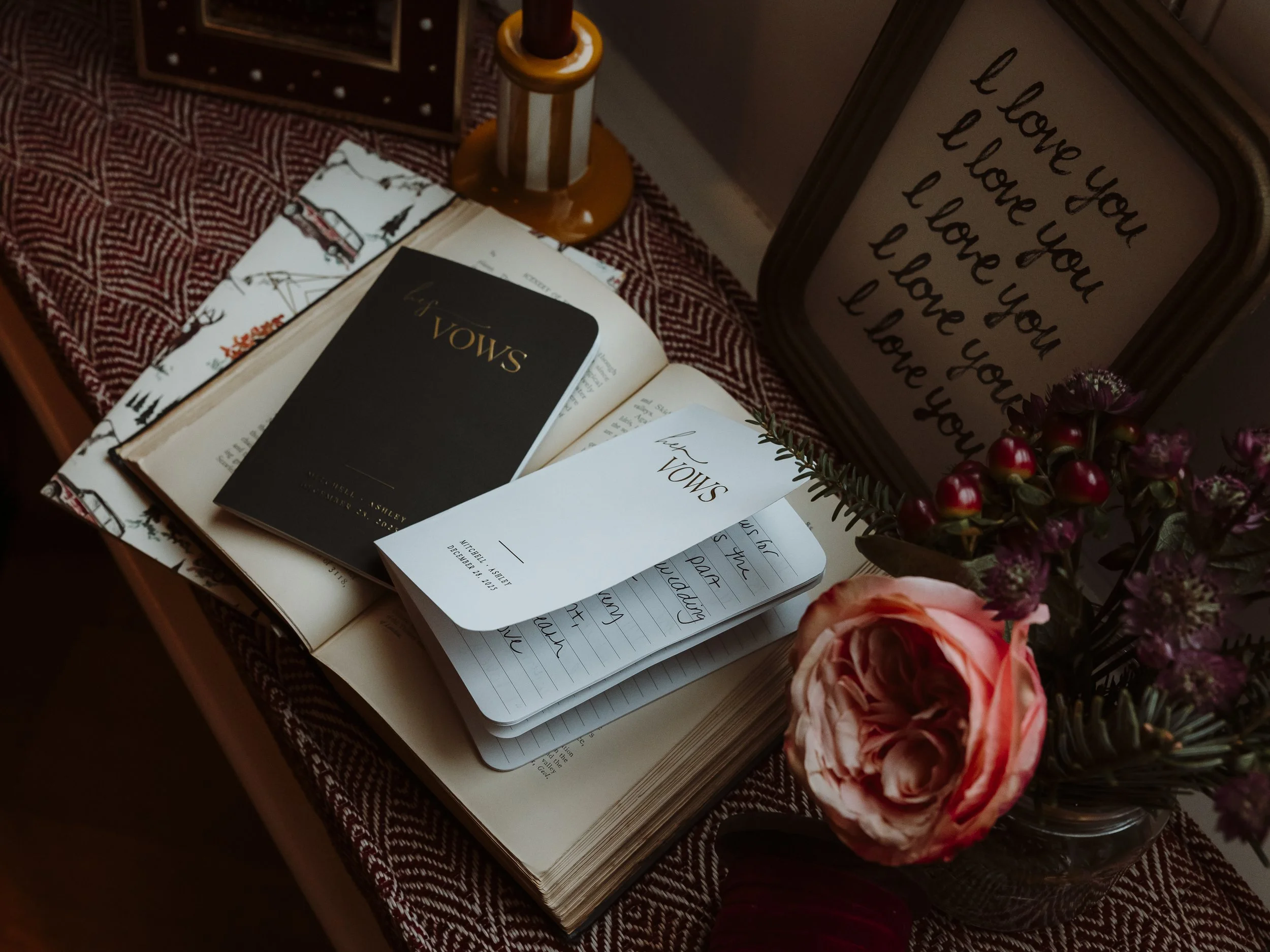 Wedding vow books and handwritten vows displayed on a bedside table with flowers and candles at The Other House in South Kensington before a London elopement.