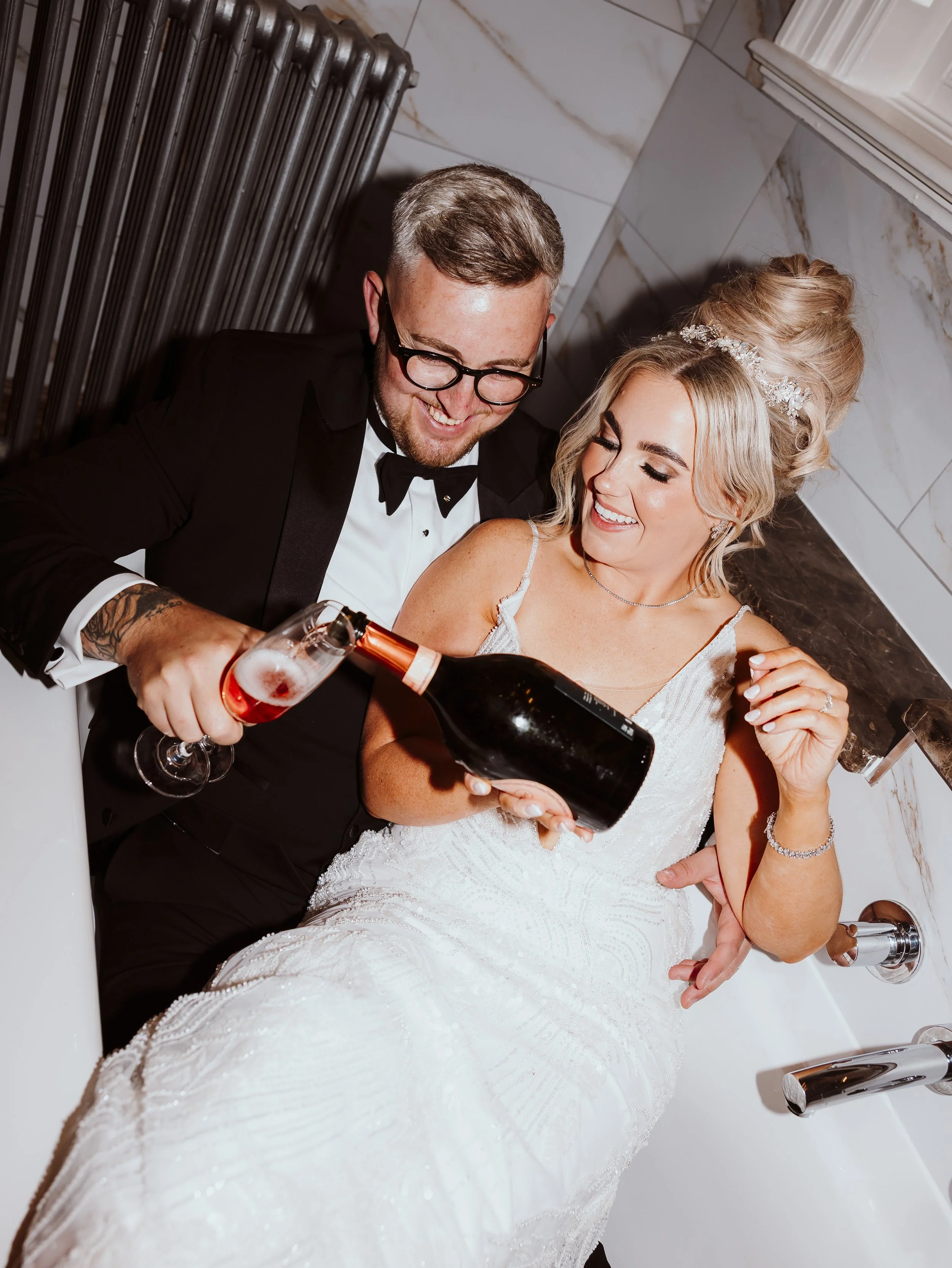 A newly married couple drinking champagne together in a bath tub at their wedding venue in Swansea, South Wales