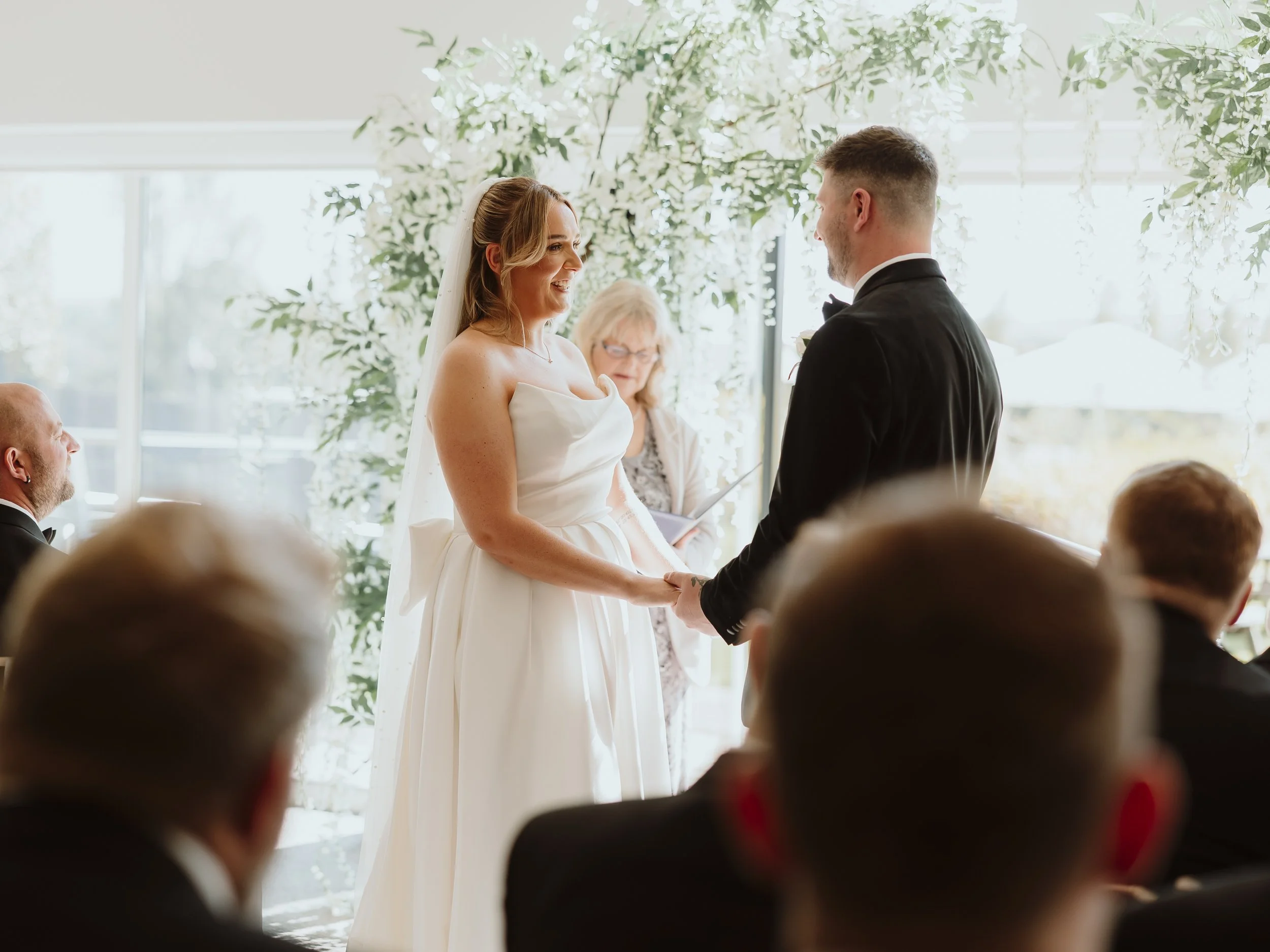 Bride and groom holding hands during an indoor ceremony at Llanerch Vineyard, South Wales