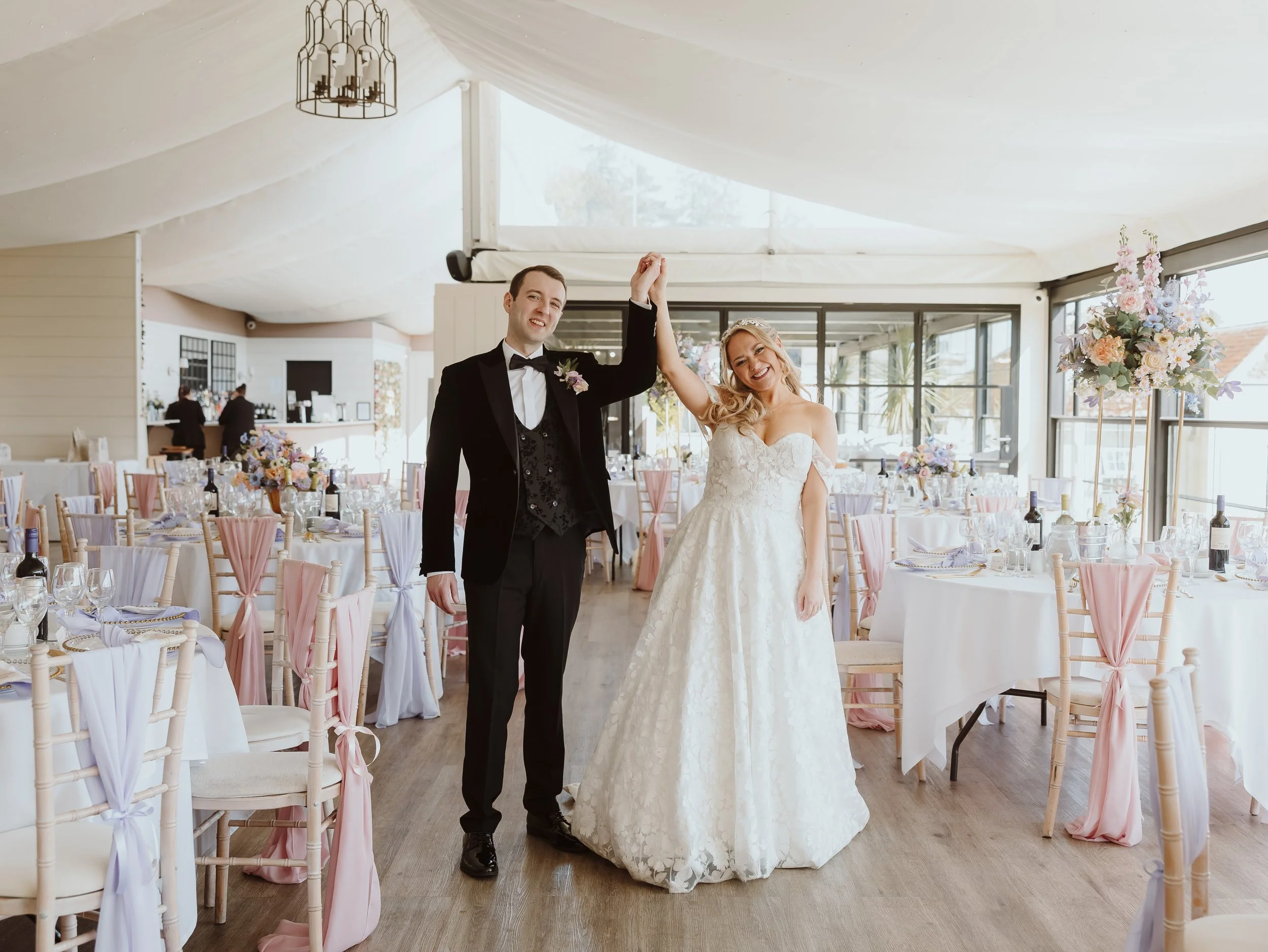 A portrait of a newly married couple holding hands in excitement as they stand in their wedding venue New house country hotel.