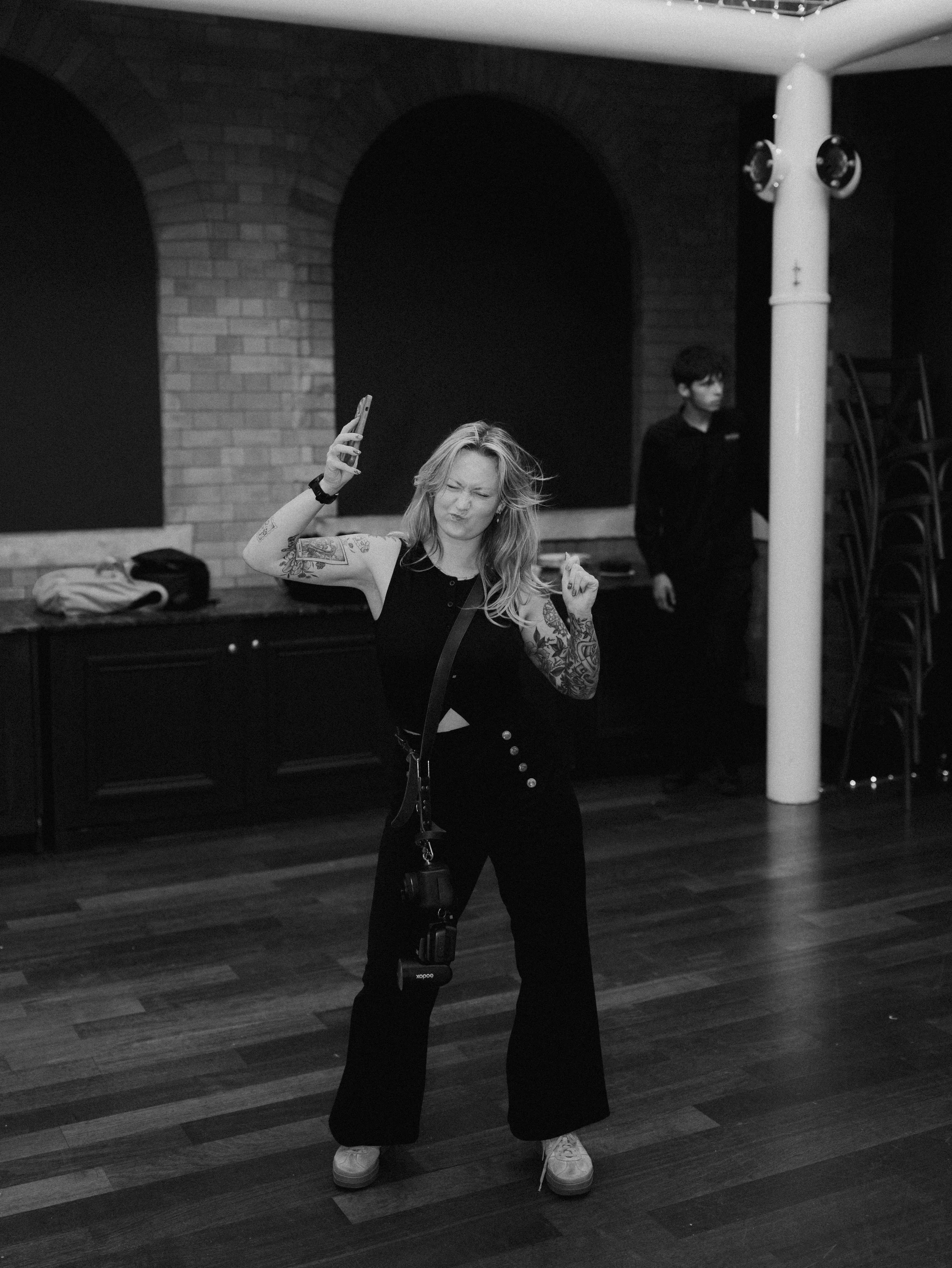 A black and white image of a Worcestershire based wedding photographer dancing while taking wedding day photos of a couple