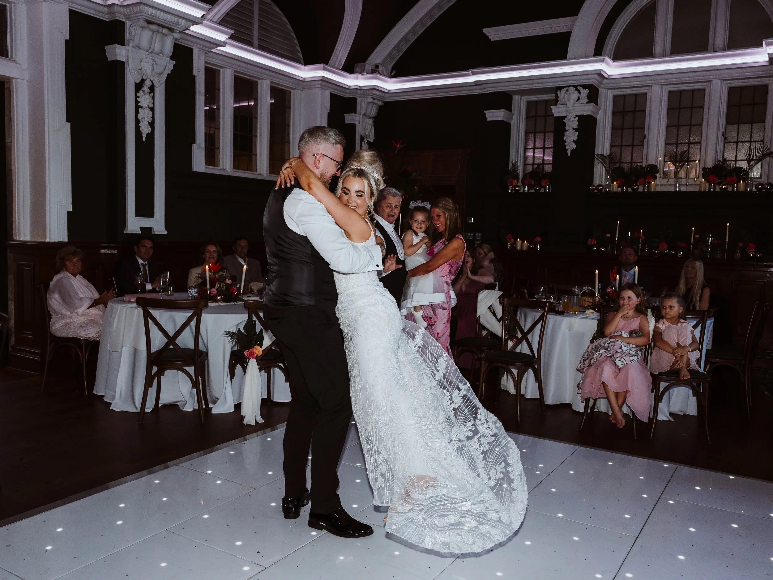 A bride being swung around by her new husband on the dance floor during their first dance