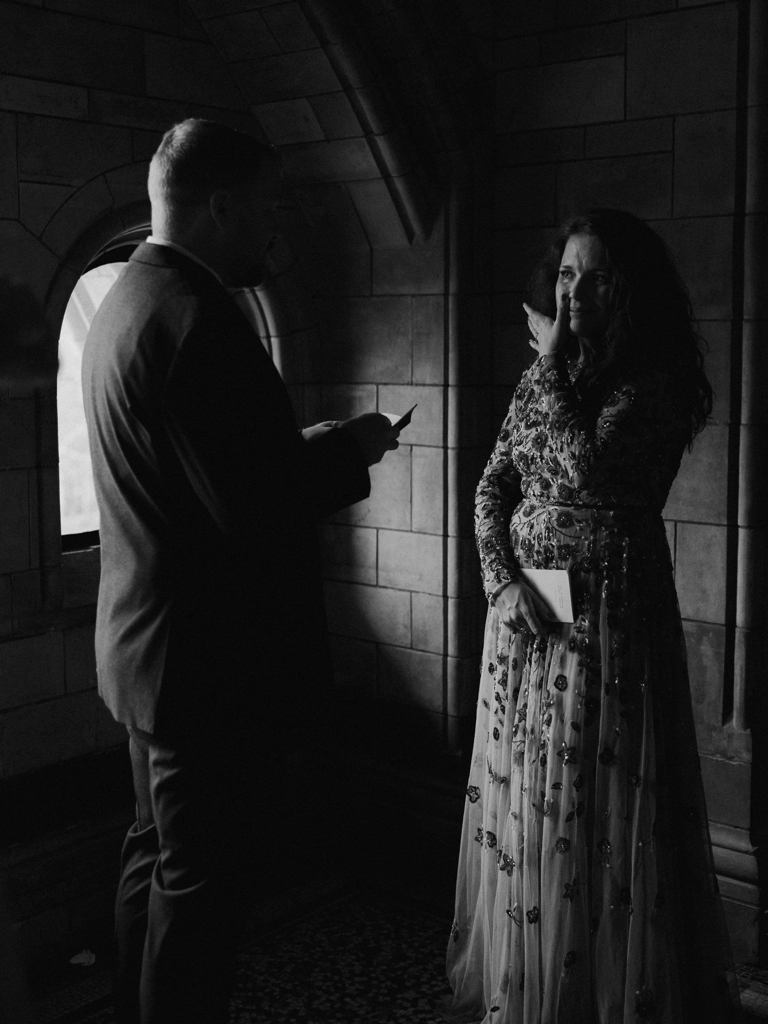 Bride wiping away tears as her groom reads his vows inside the Natural History Museum during their intimate London elopement.