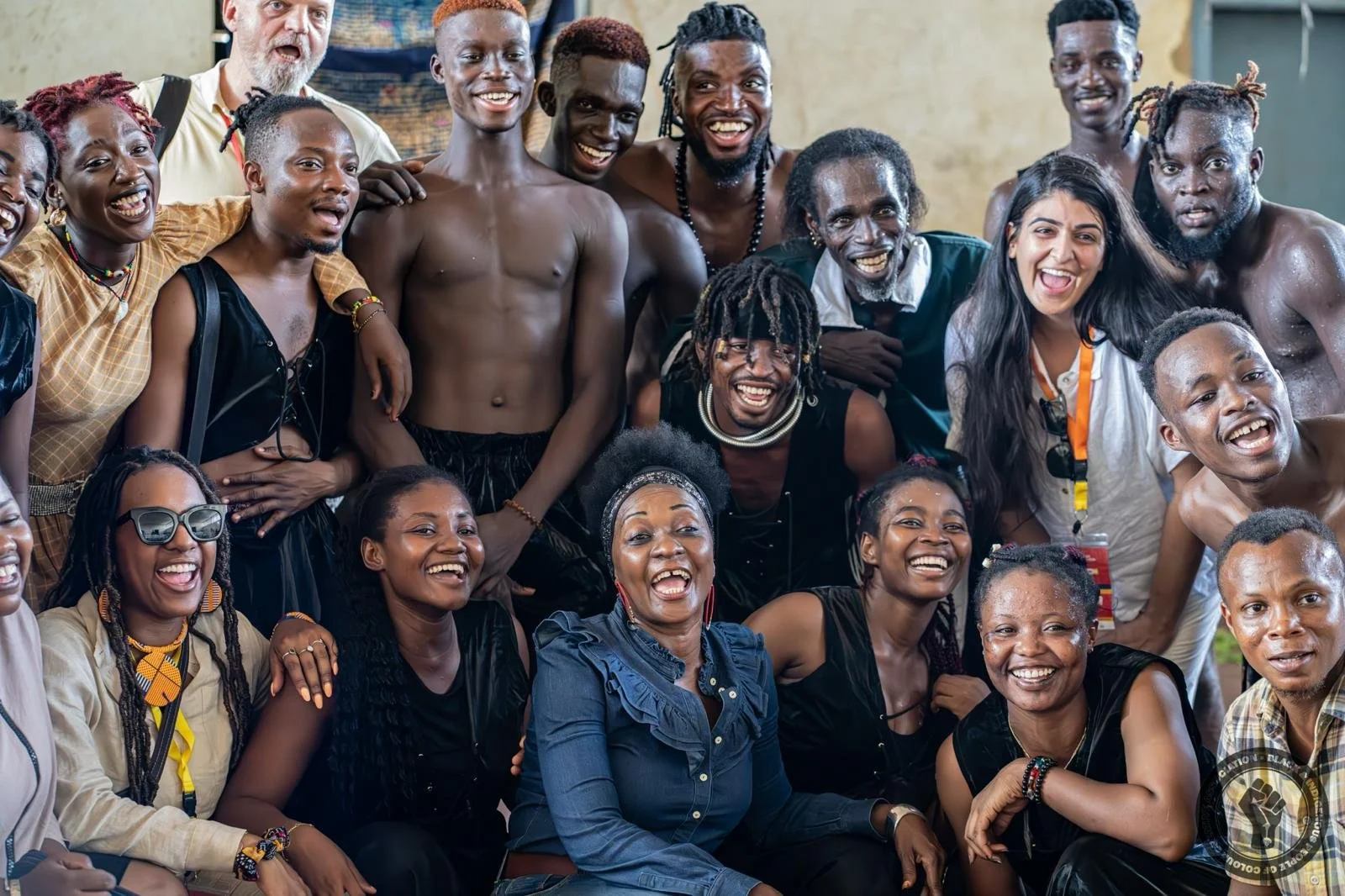 A diverse group of smiling people enjoying a gathering indoors, some wearing colorful accessories, and lively expressions.