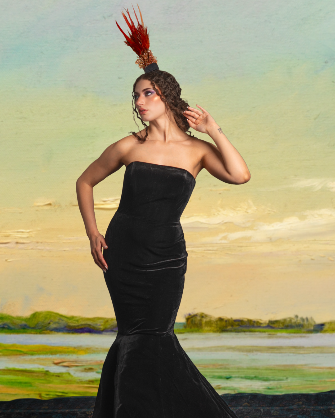 A woman in a strapless black velvet gown and an ornate headpiece with red feathers standing in front of a painted landscape background.