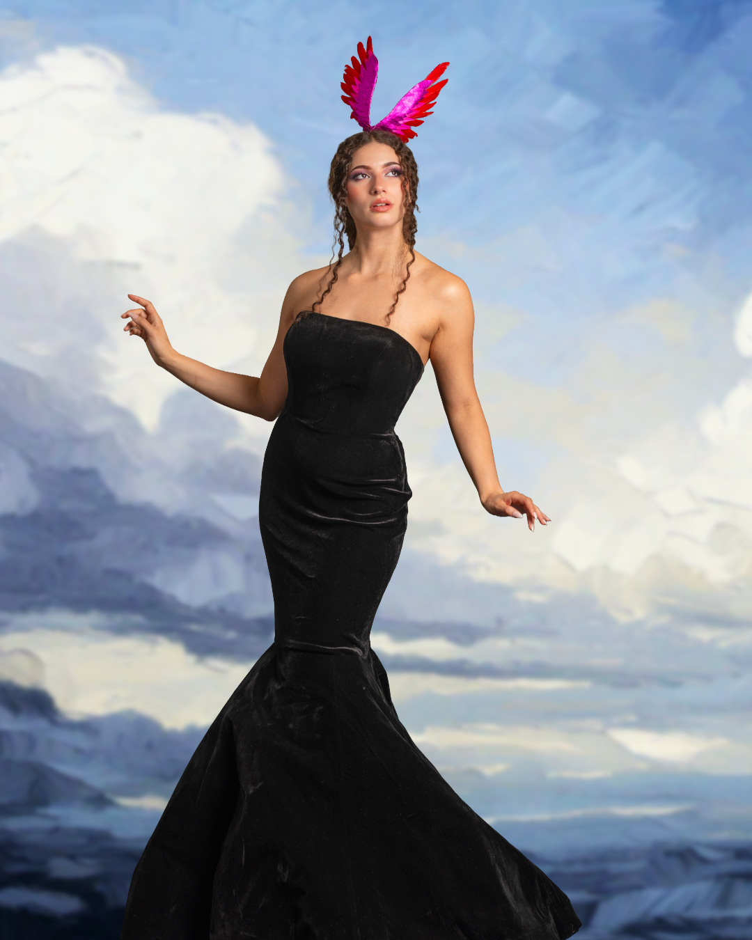 A woman in a black strapless gown with pink and red feathered headpiece stands against a cloudy sky background.