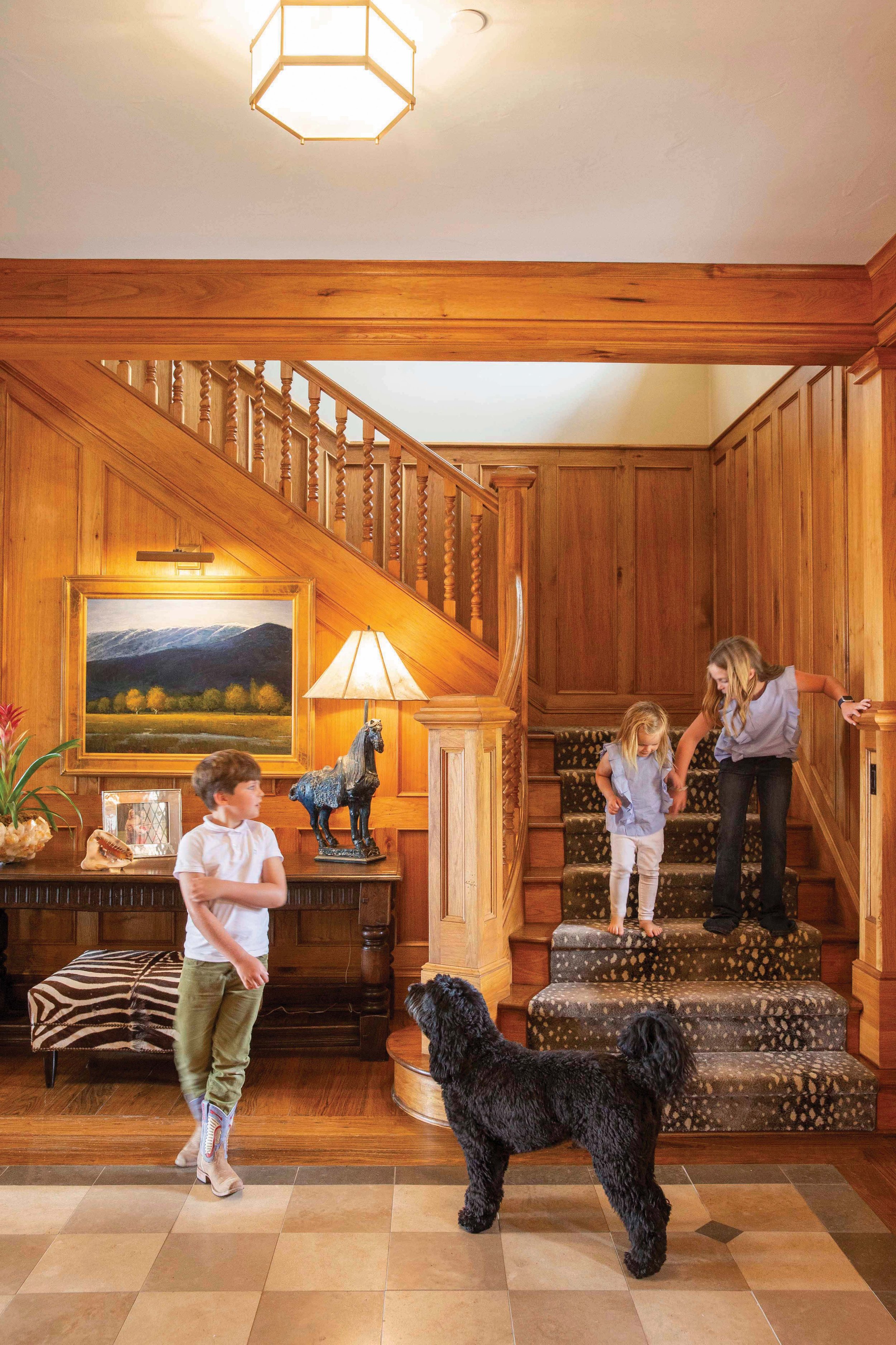  Wood paneling and an elaborate balustrade bring warmth to the oversize staircase in the ranch house. 