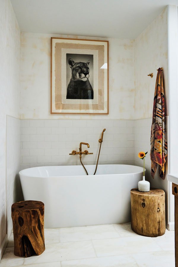  A mountain lion print on handmade paper by Jennifer hangs above a stand-alone tub with reclaimed wood stumps by Henderson. 