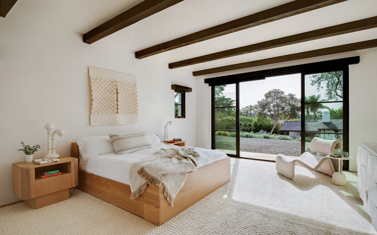  IIn the primary bedroom, a wall hanging by Mary Little overlooks the bed flanked by nightstands (all by Community Manufacturing). A lounge chair by Forom and side table from Garde provide a reading spot with garden views. 