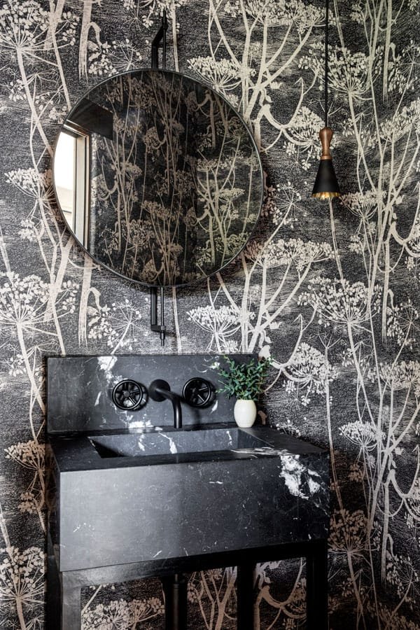  The dramatic black-and-white powder room is covered in Cole &amp; Son wallpaper. 