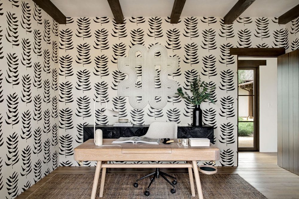  Wallpaper from The Cartelier makes a strong statement in the office. A graphic wall piece by Lawson Fenning is suspended over a credenza by Ethnicraft. A chair by Lulu and Georgia fronts a desk from Garde. The desk lamp is by Lawson Fenning. 