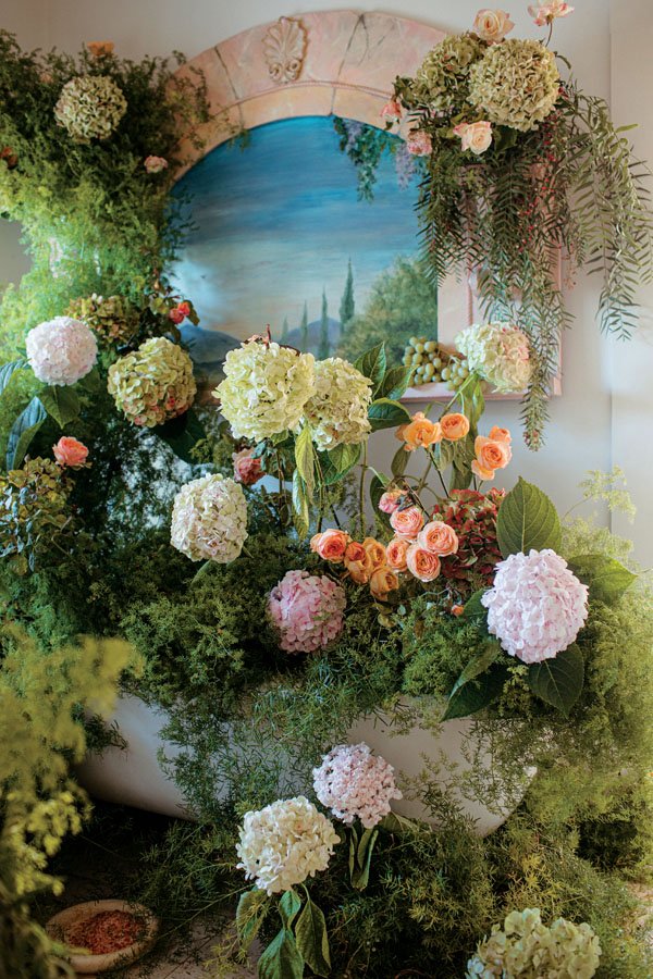 Ojala Floral took a cue from a wall painting for their arrangement of roses and hydrangeas in the primary “palazzo” bath. 