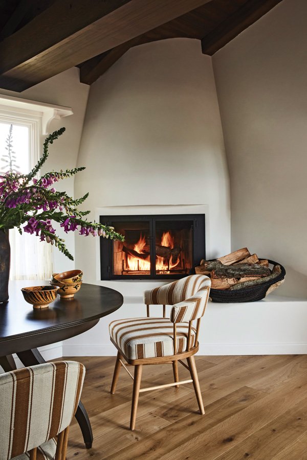  The existing fireplace surround in the breakfast nook was refreshed by J2 Interiors with custom plaster; dining table by Rose Tarlow; Nickey Kehoe chairs covered in Classic Cloth Point Stripe. 