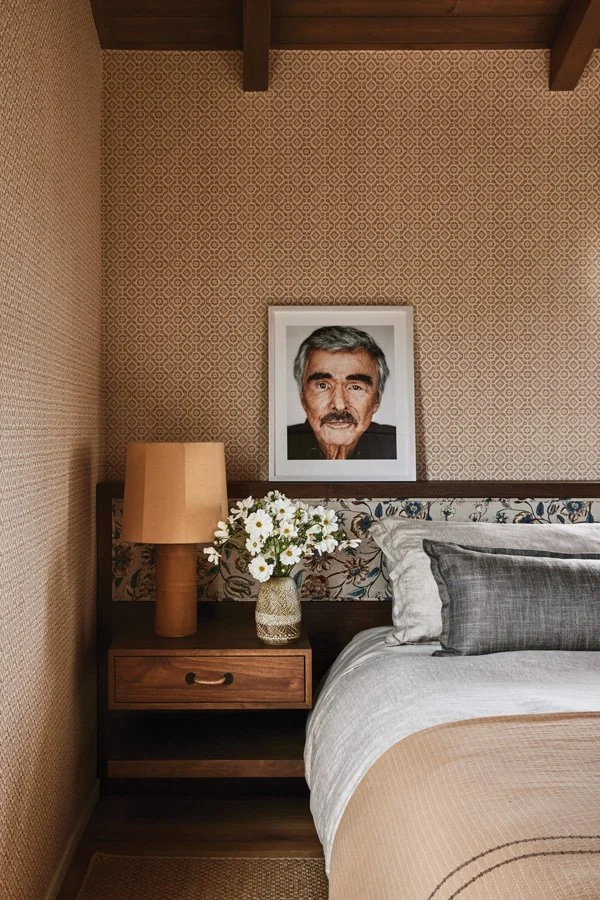  A 2015 portrait of Burt Reynolds by Martin Schoeller sets the tone in the upstairs guest bedroom; Sonora table lamp by Nassi Lamps; custom bed with floating nightstands by J2 Interiors; Donatello Framboise wallpaper by Nicholas Herbert. 