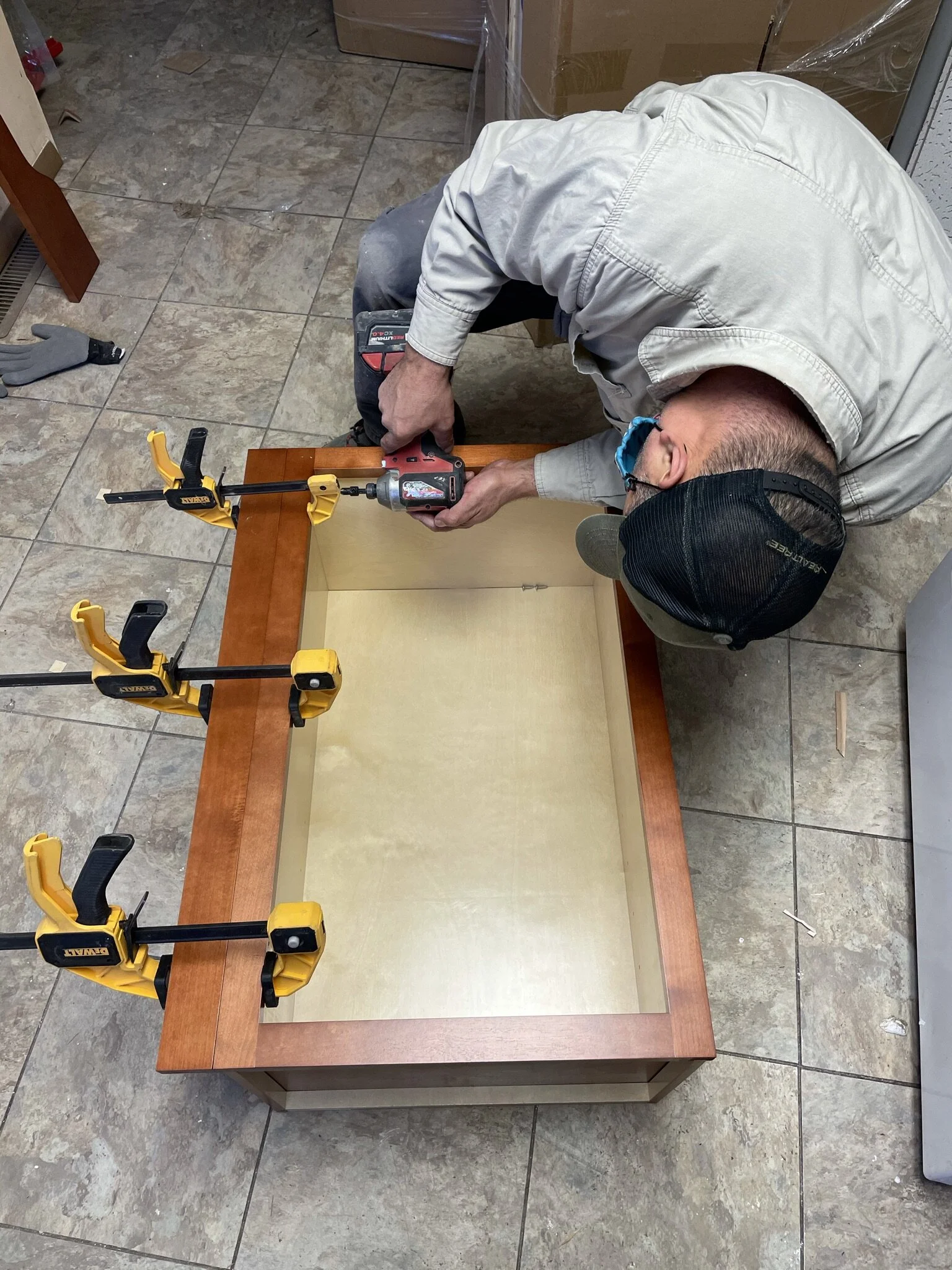A man using a drill to assemble a wooden furniture piece in a workshop