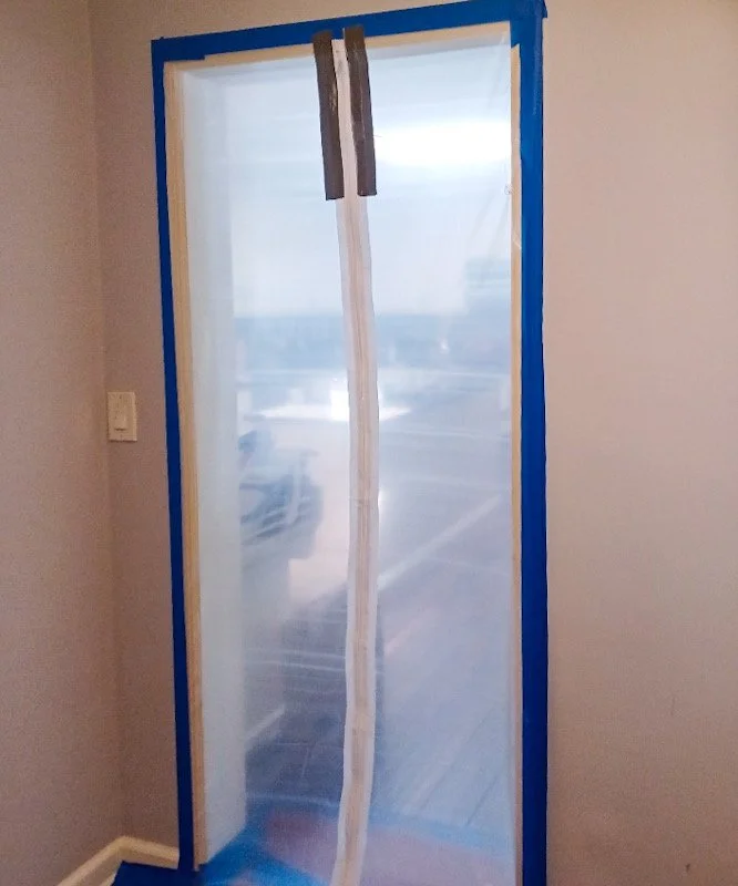 A sliding glass door with blue painter's tape around the edges and masking tape down the center, indicating it is under repair or installation.
