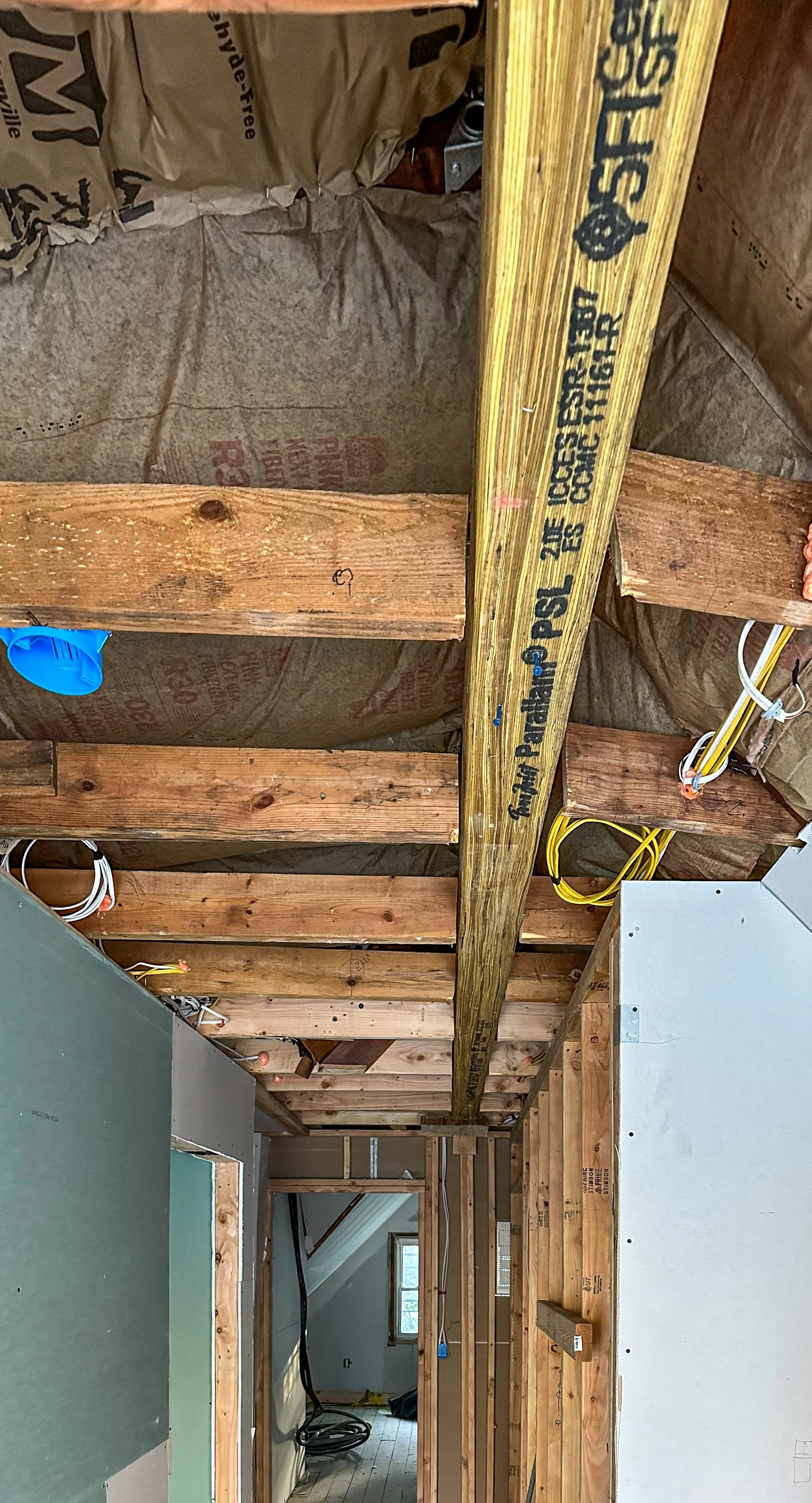 Interior view of a construction site with exposed wooden framing and electrical wiring, showing an unfinished room in a building under renovation.