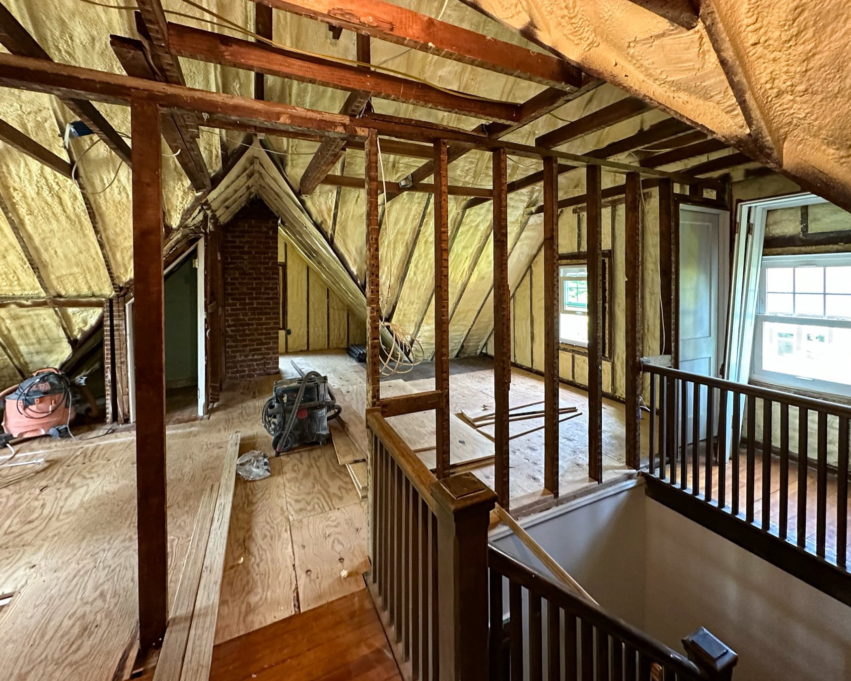 Interior of a house under renovation with exposed wooden framing, insulation, and windows.