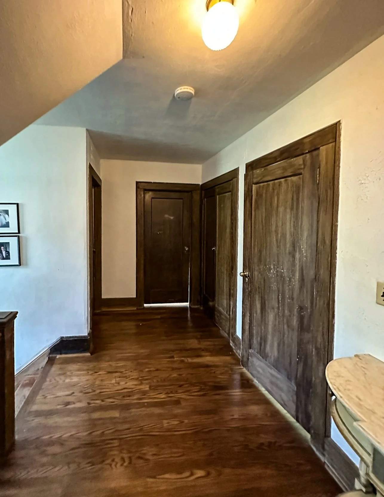 Wooden closet doors inside a room with hardwood flooring and white walls, with a small round table on the right side.