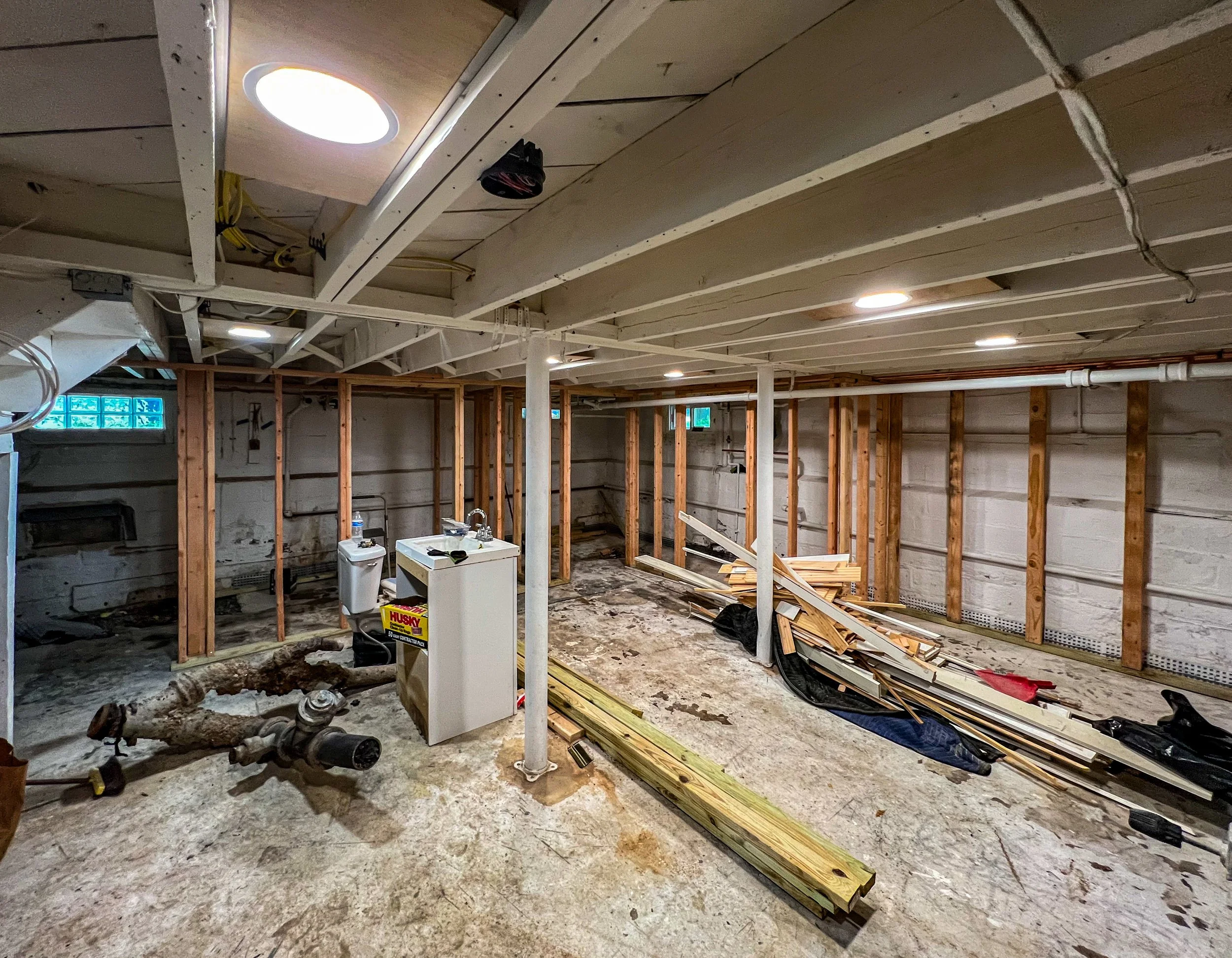 unfinished basement with exposed wooden studs, construction materials, and a concrete floor.