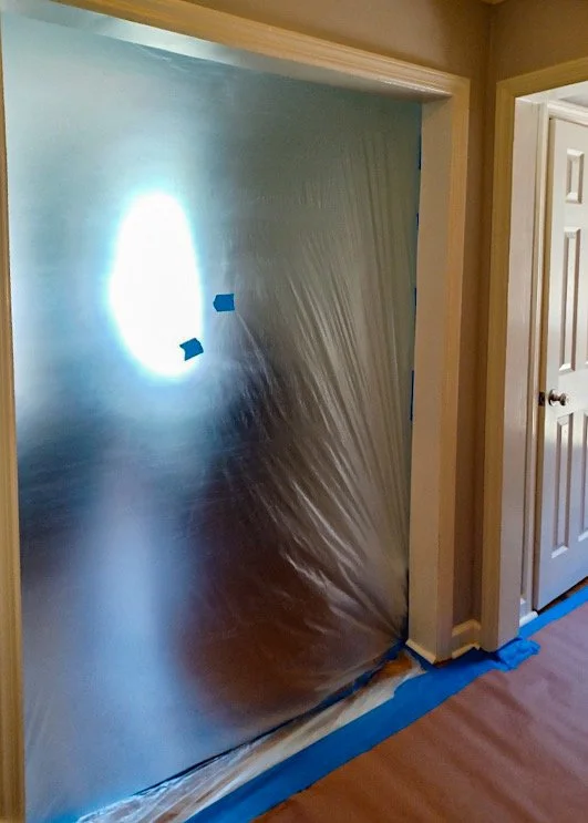A doorway covered with protective plastic sheeting during painting or renovation in a home.